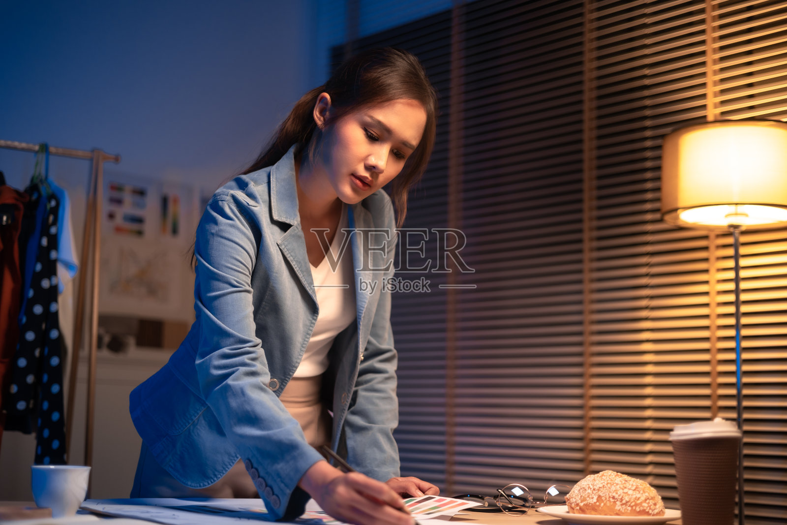 年轻漂亮的女人在黄色衬衫工作很晚从家里的客厅深夜加班。女商人在工作场所低头看电脑。照片摄影图片