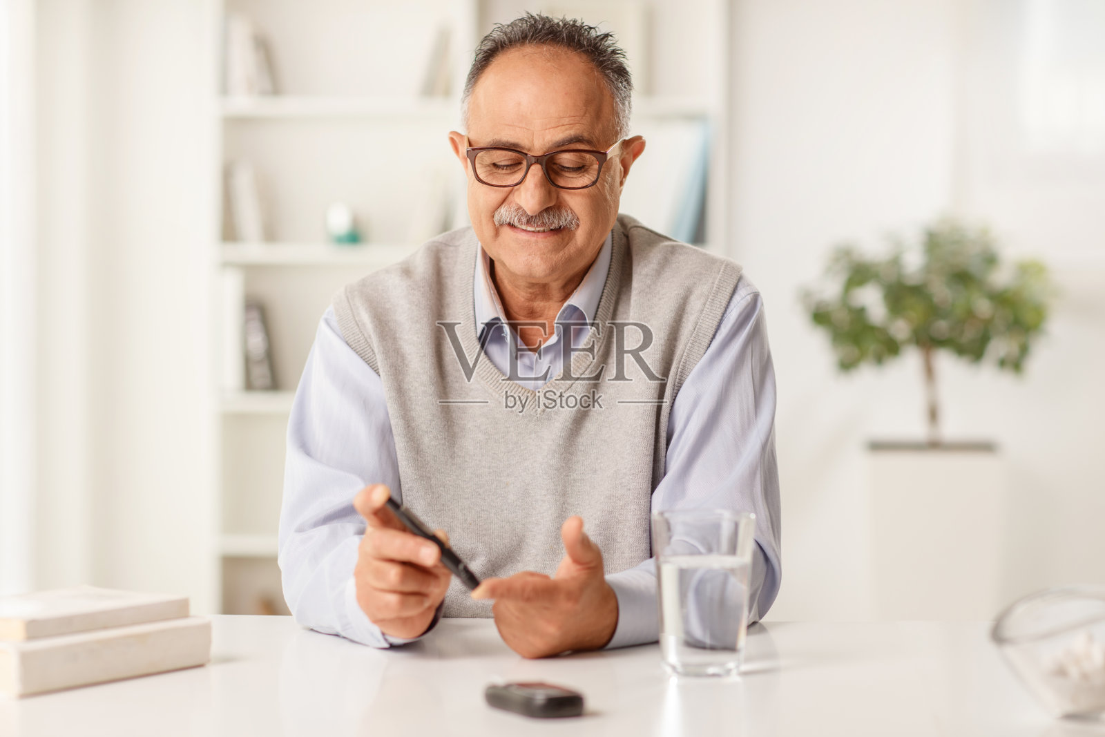 坐在家中检测血糖水平的中年男人照片摄影图片