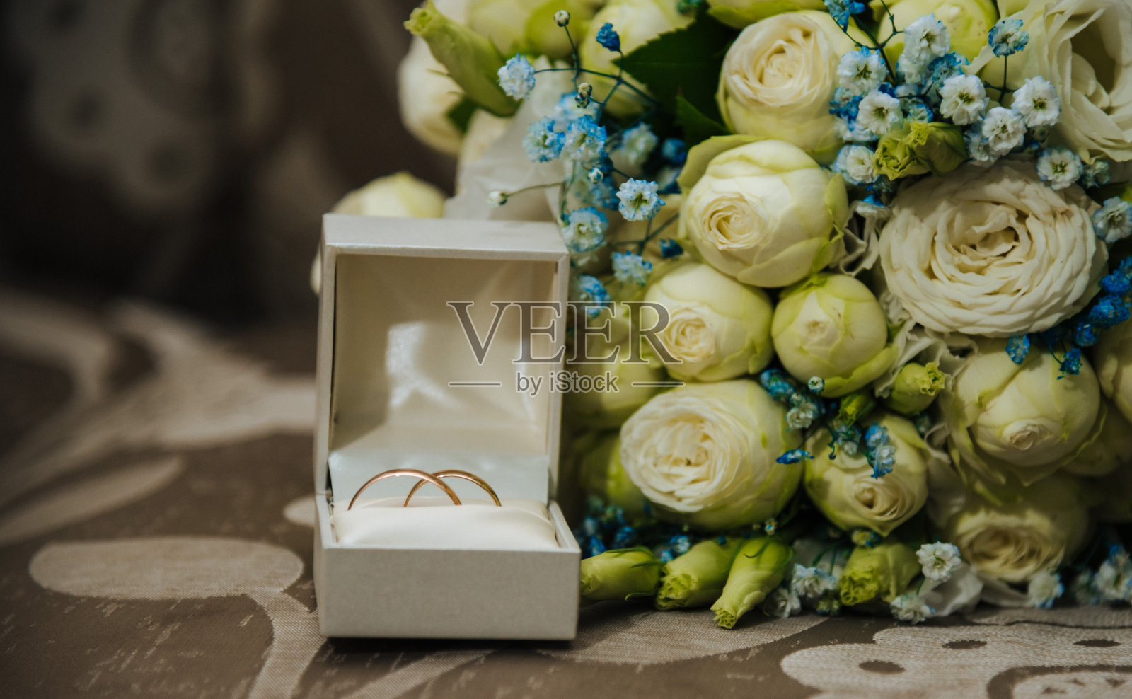 灰色背景上有粉色花朵的结婚戒指照片摄影图片