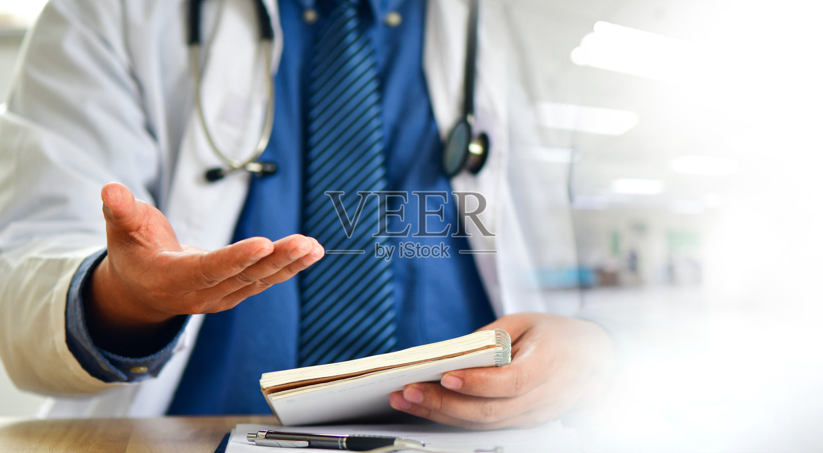 医生坐在镜头前,坐在办公室里给他的病人提供在线咨询。照片摄影图片