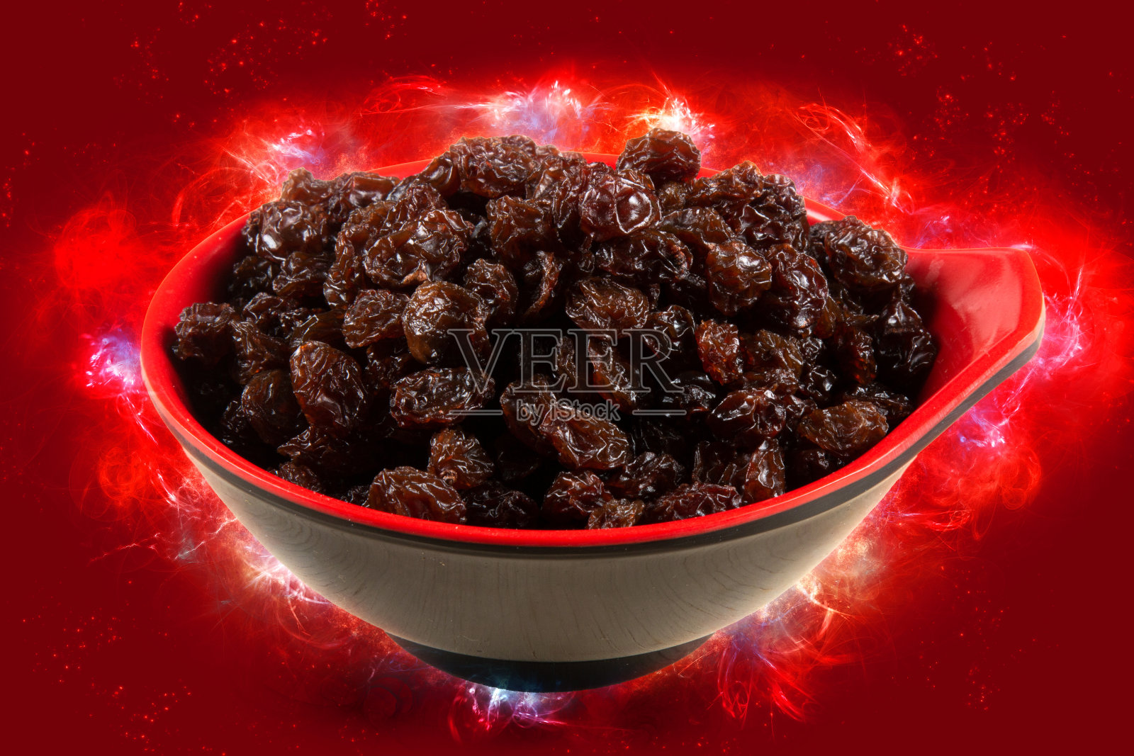 风干的葡萄干。典型的圣诞食物。红色背景加上灯光效果照片摄影图片