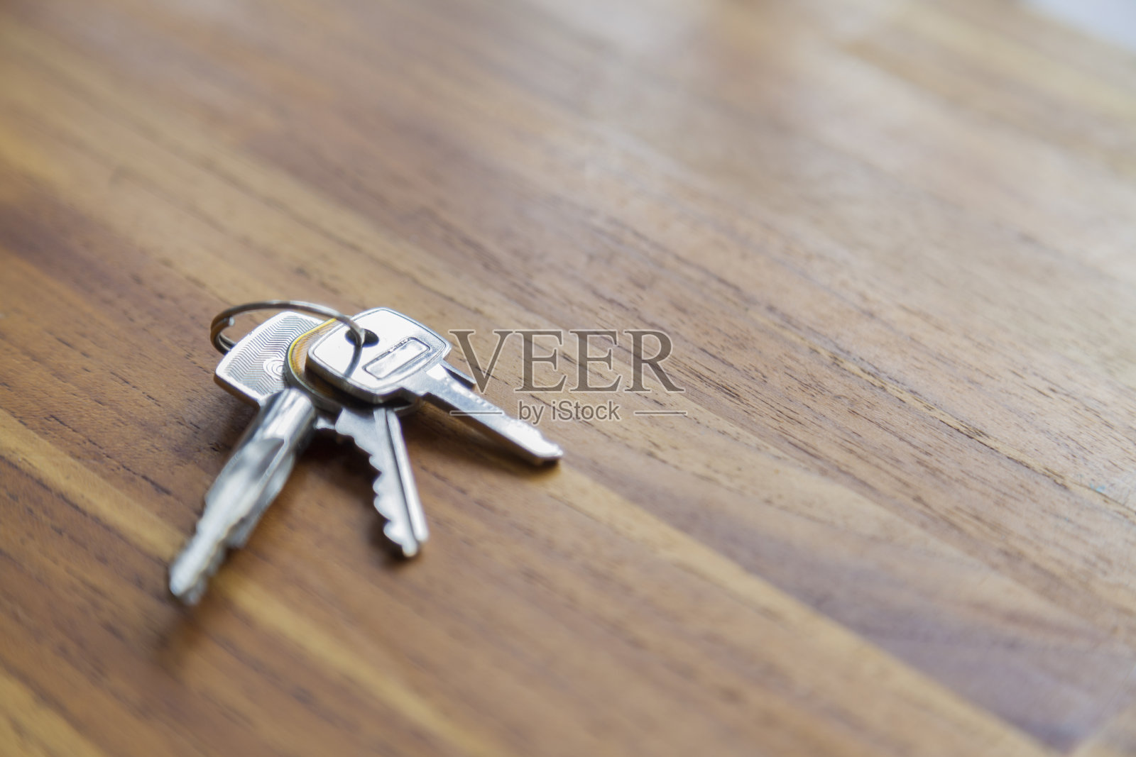 房门钥匙放在木桌上。照片摄影图片