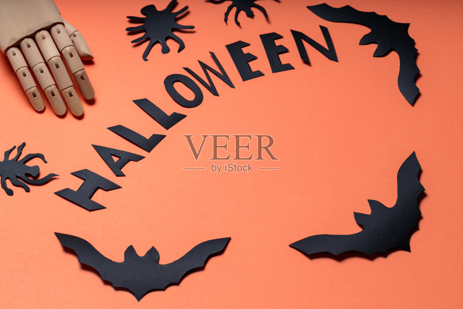 万圣节的概念与人工手臂,蝙蝠和蜘蛛在橙色的背景。万圣节用木手和蝙蝠的图案书写。本空间照片摄影图片