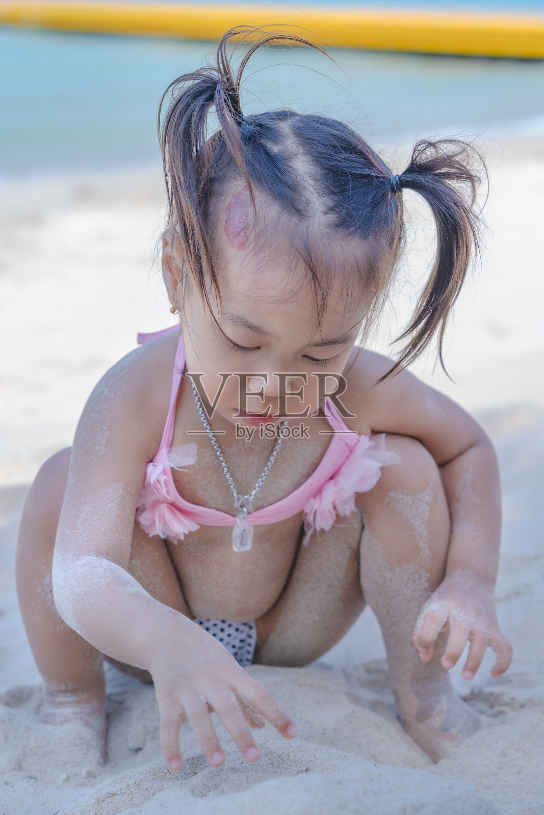 特写可爱的快乐的小女孩玩沙滩在夏季热带假期。可爱的亚洲小孩穿着泳衣在沙滩上玩沙子。照片摄影图片