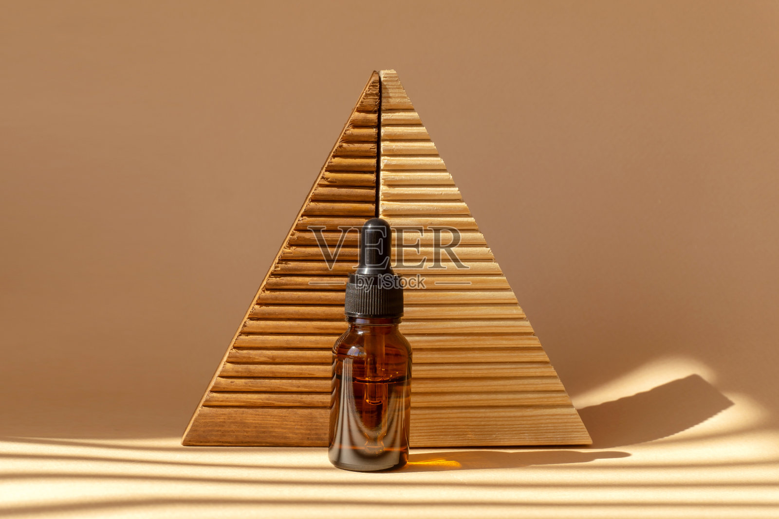 一瓶精油和木制槽平台在阳光照射下的棕色背景。天然化妆品,无标记容器,带滴管盖。的概念模型照片摄影图片