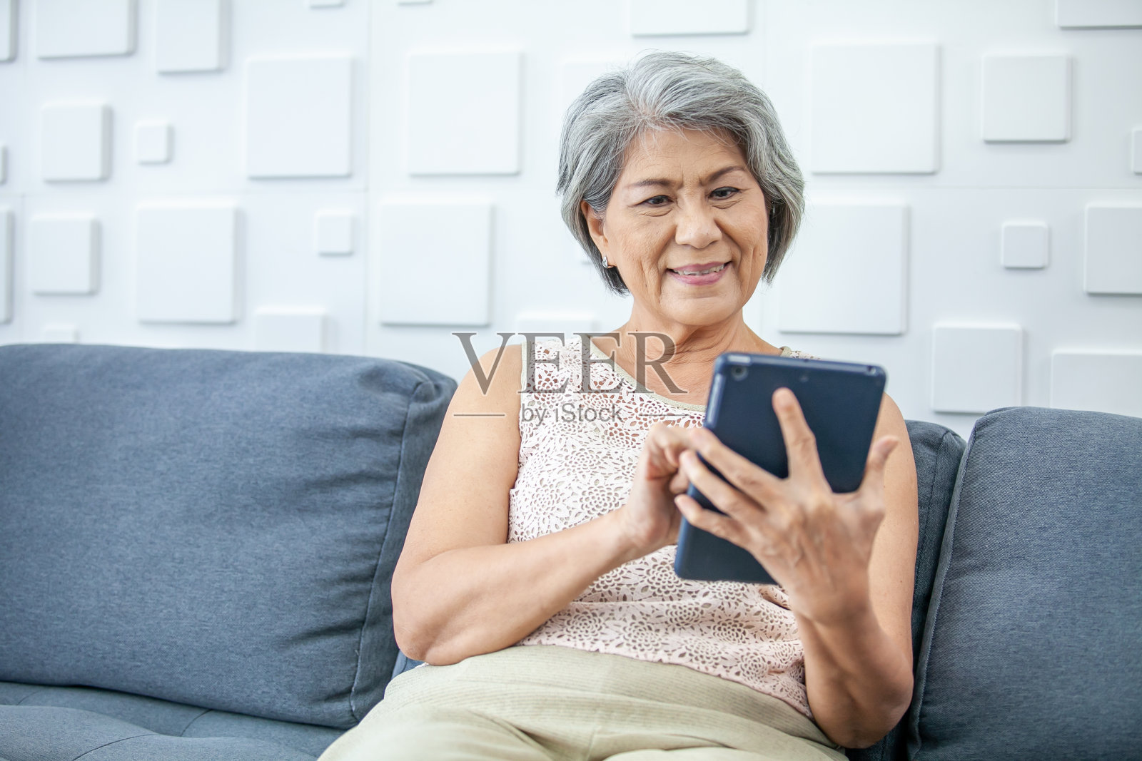 头发花白的亚洲女性正拿着智能手机使用在线应用程序或在网上购物。照片摄影图片