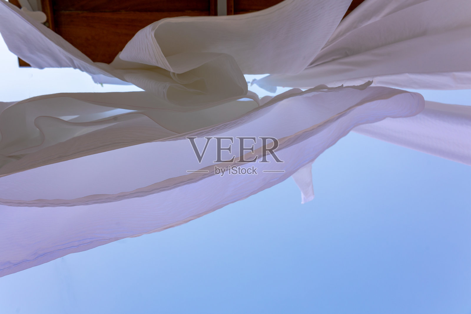 希腊塞米岛渔村的晾衣绳上晾晒着白色亚麻。雪白的床单在风中散落。底视图照片摄影图片