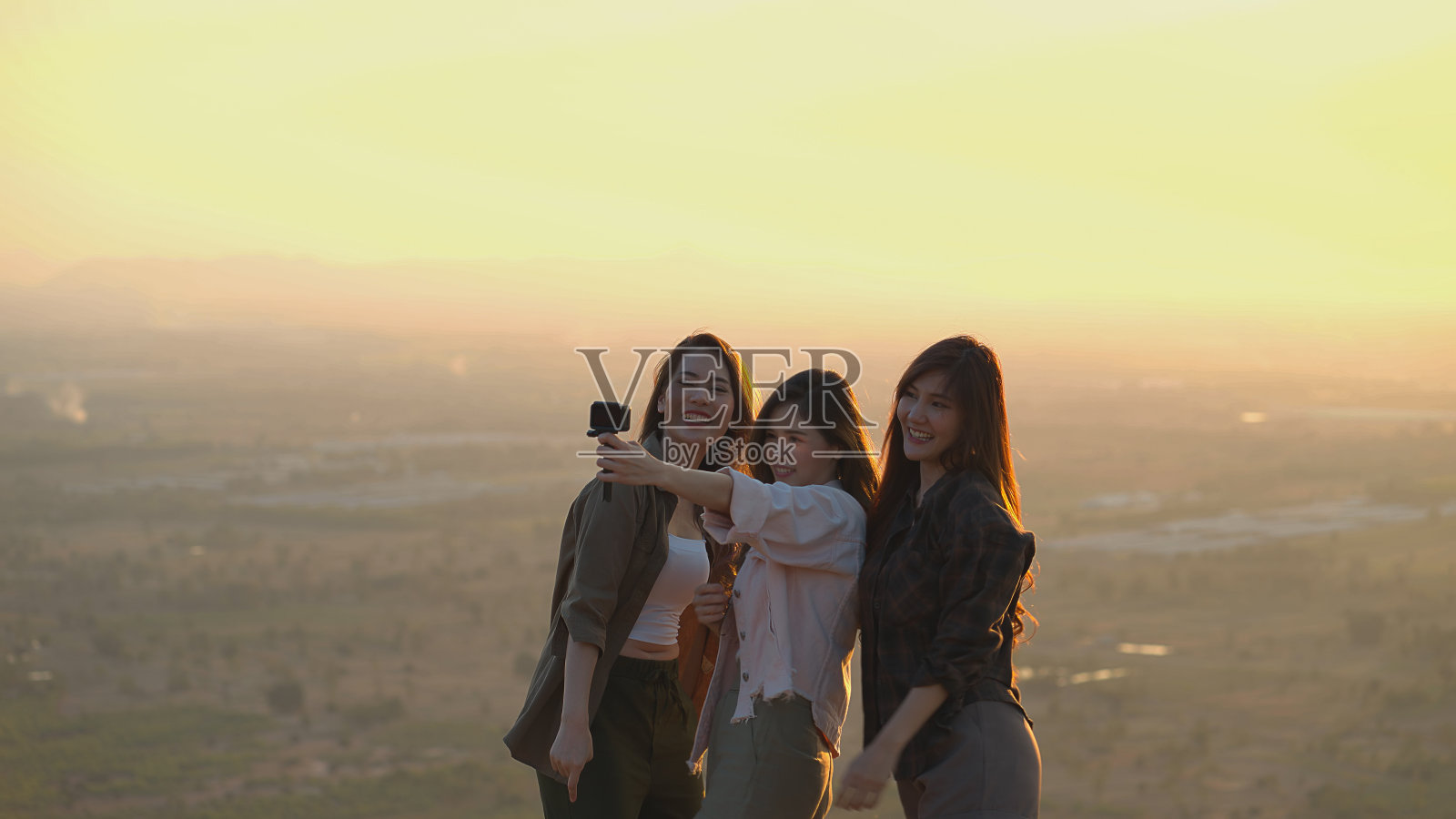 亚洲年轻女性在日落时分欣赏视频博客。视频还照片摄影图片