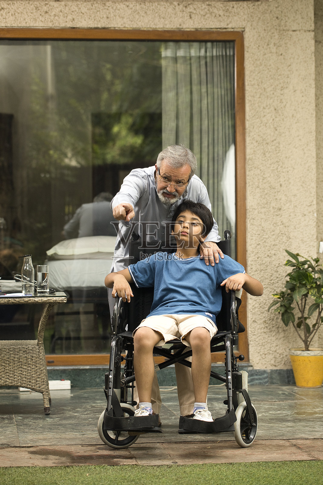 爷爷和残疾的孙子坐在轮椅上照片摄影图片