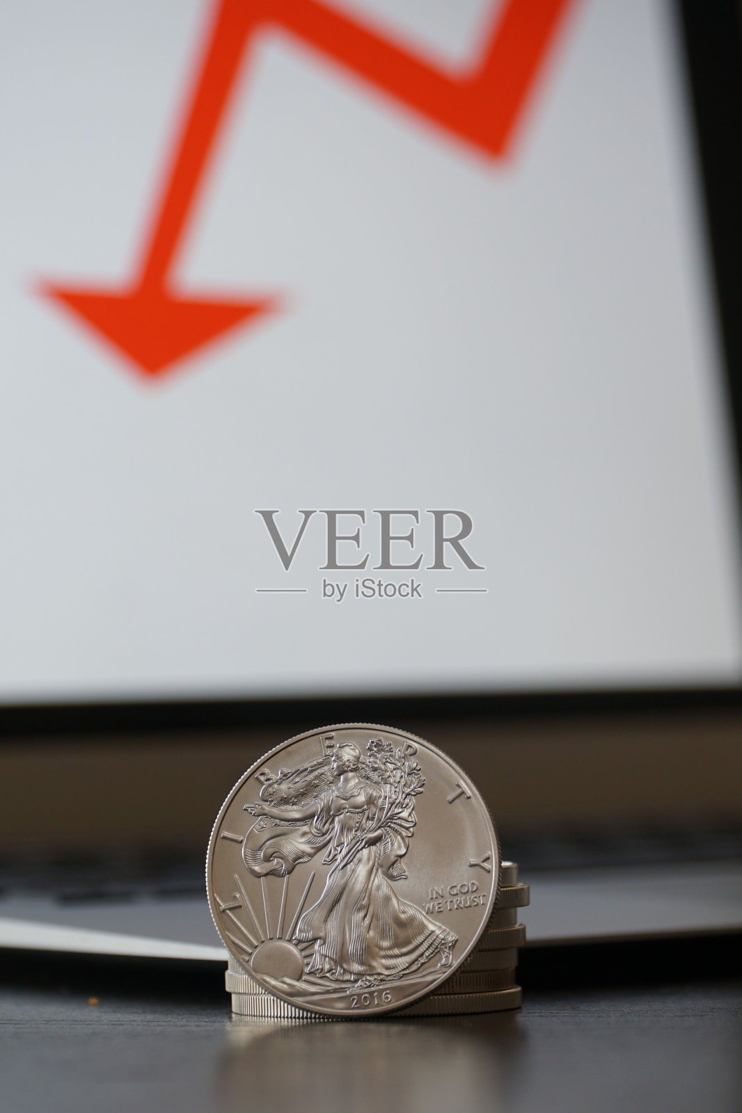 特写的银币与下降的价值与计算机上的红色箭头照片摄影图片