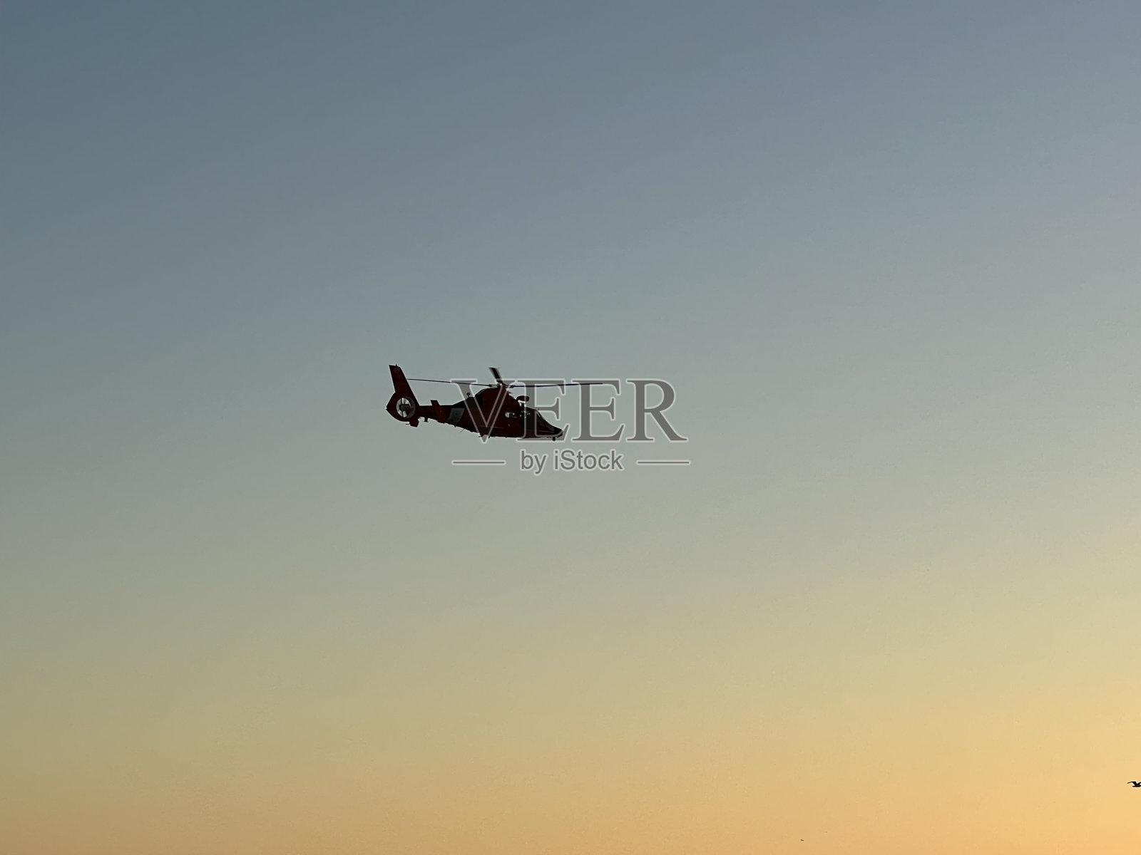 日落时分,海岸警卫队的直升机飞过威尼斯海滩照片摄影图片