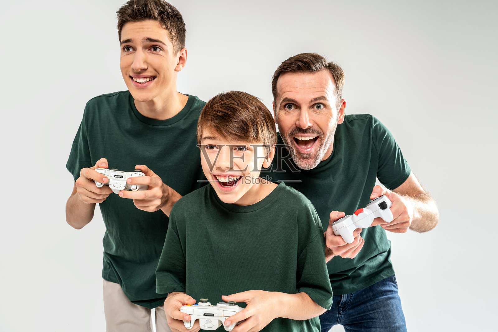 两个小男孩和他的父亲正在玩游戏机,看着镜头微笑照片摄影图片