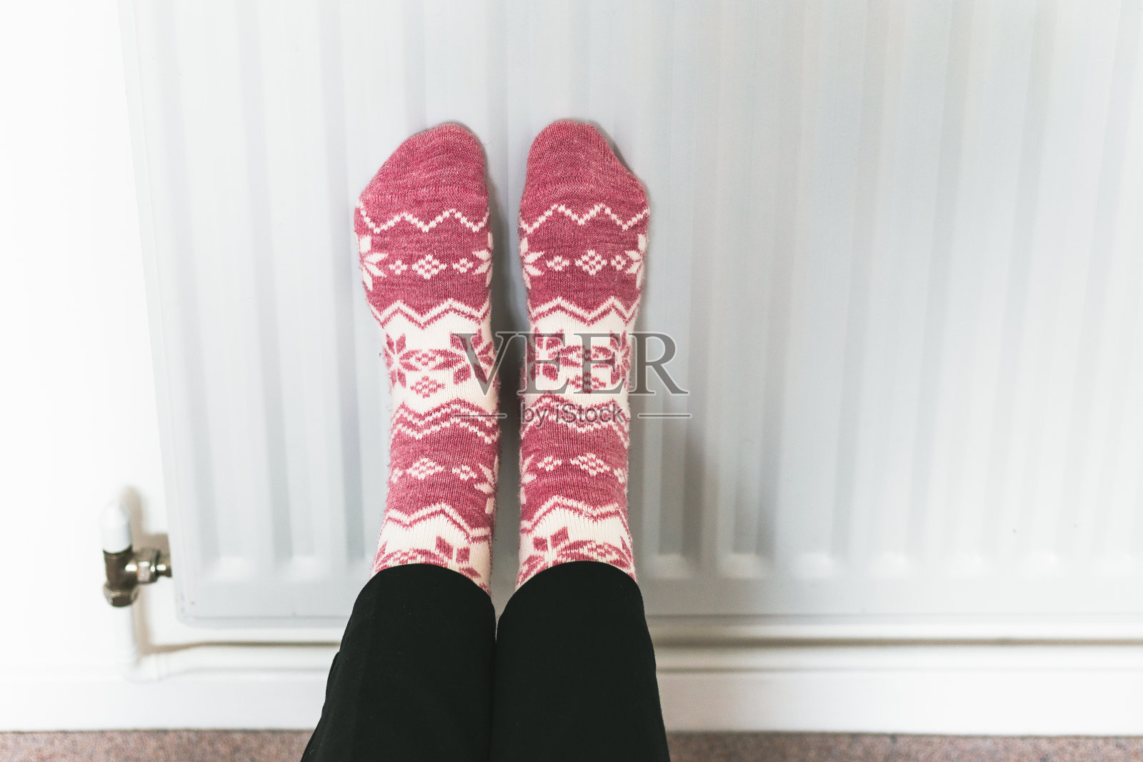 穿着冬天的袜子在暖气片上暖脚照片摄影图片