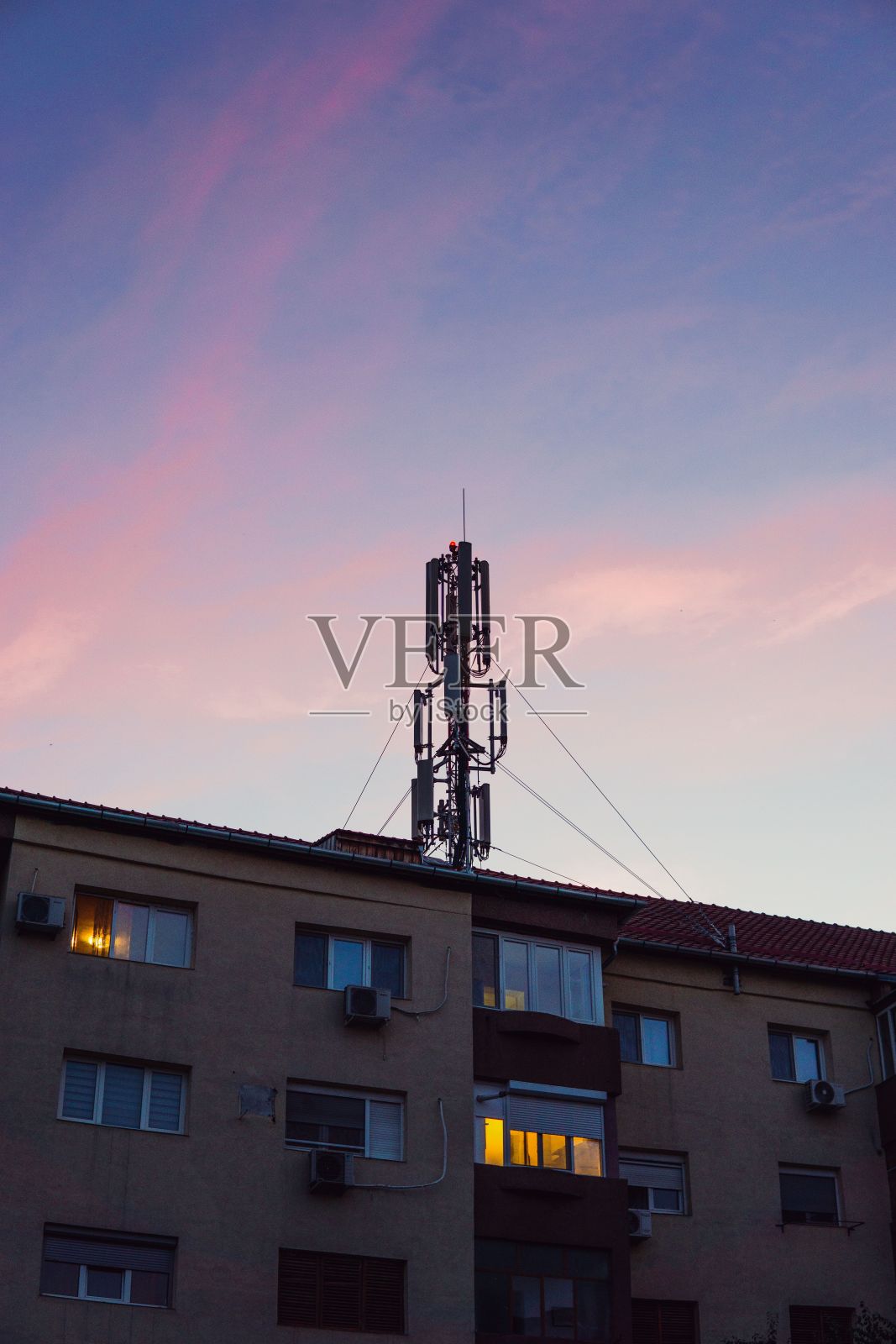 公寓大楼顶上的基站在日落的天空下的垂直拍摄照片摄影图片