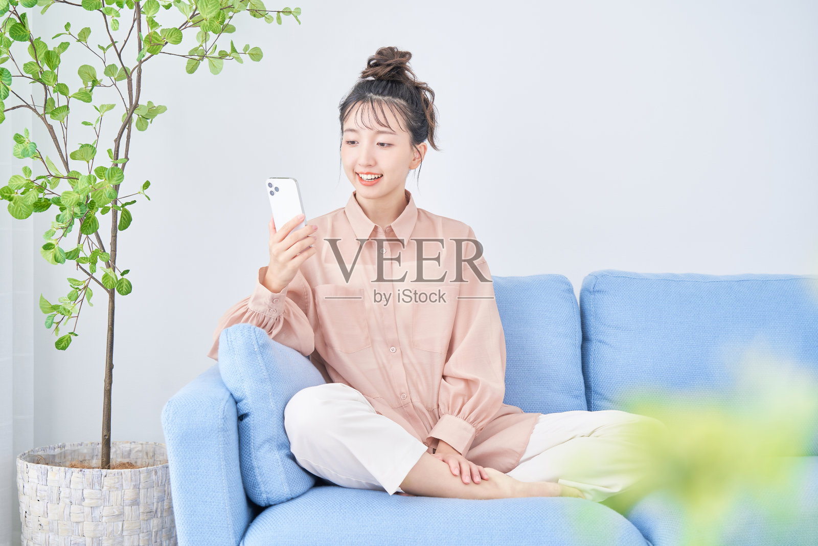 年轻女子在房间里使用智能手机照片摄影图片