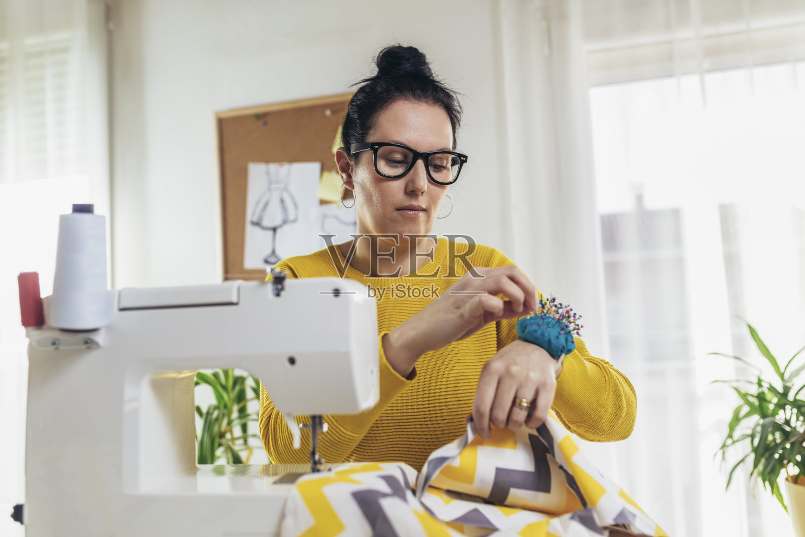一名妇女正在家里的缝纫机上缝纫照片摄影图片