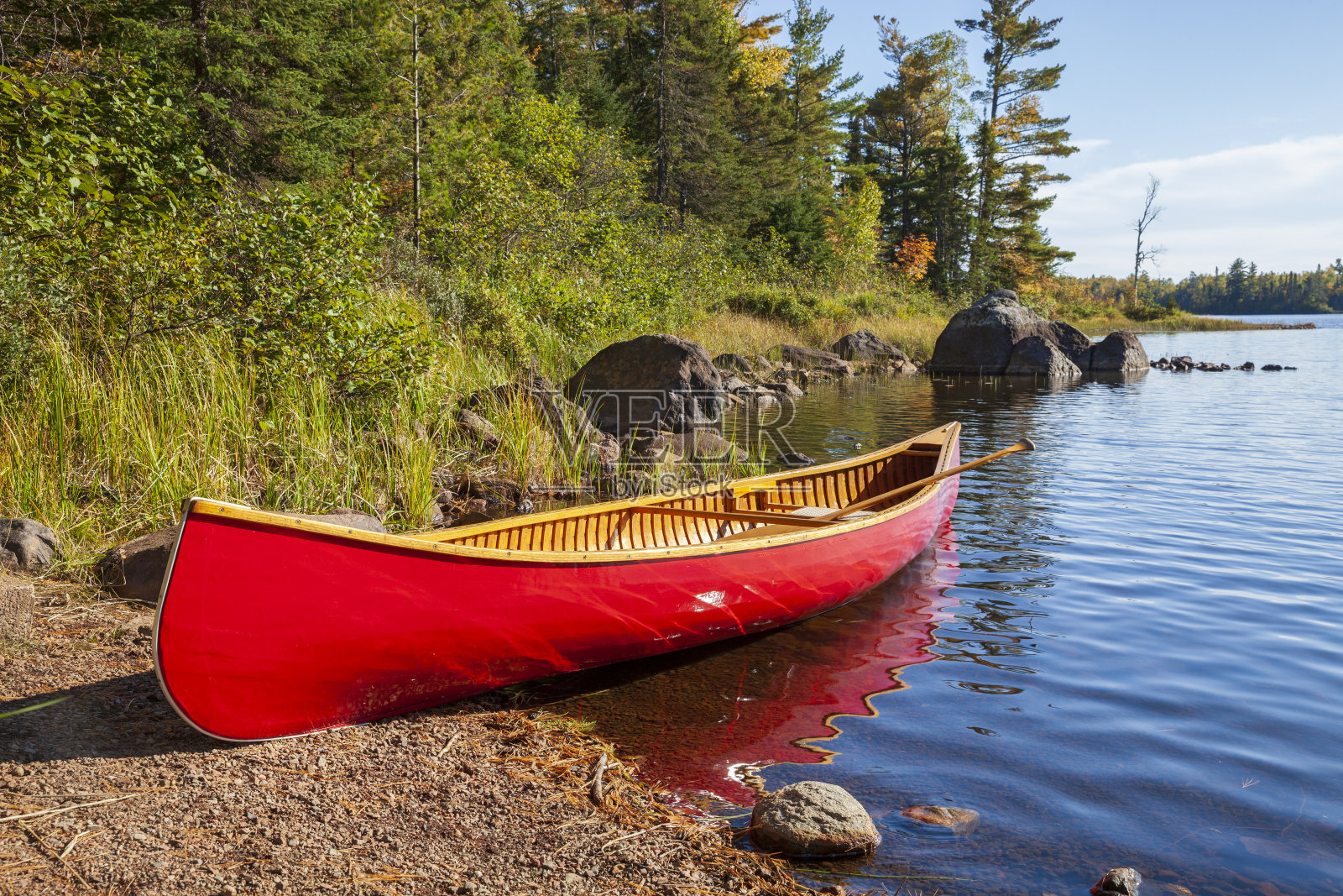 红色木独木舟在北明尼苏达湖岸边,沿岸有岩石和松树照片摄影图片