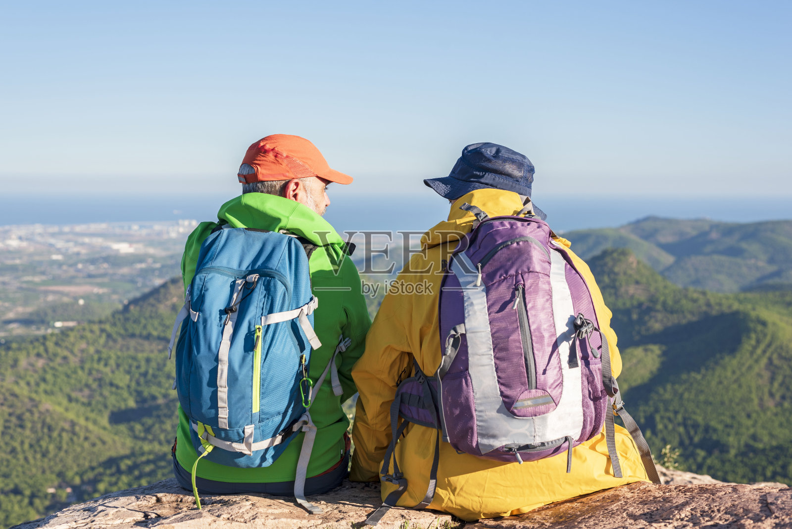 两个徒步旅行的朋友坐在山顶上,景色非常好。照片摄影图片