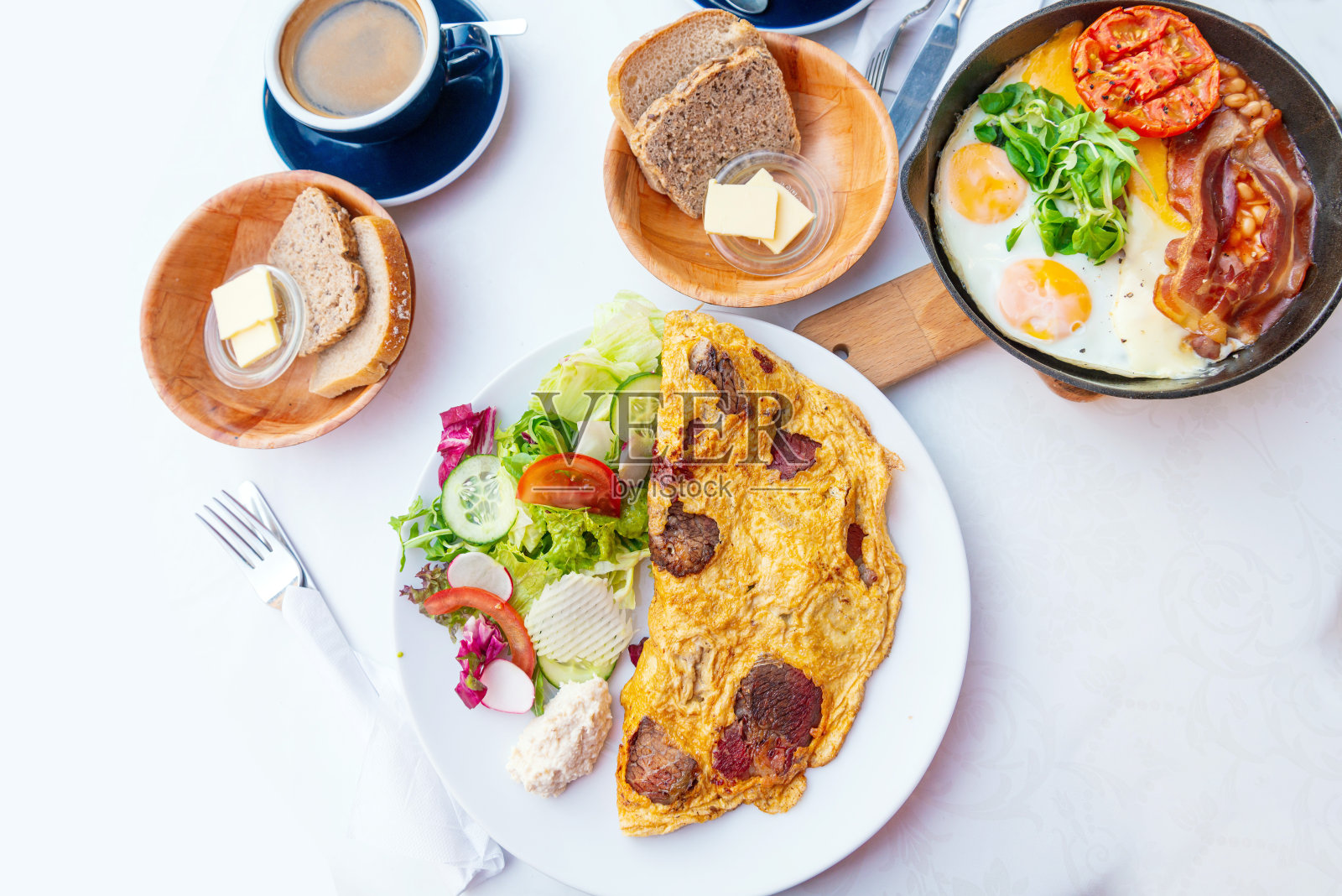 素食早餐有炒豆腐和鸡蛋,用干番茄和西葫芦烹制,配上新鲜的生菜和黄瓜,装在白色陶瓷老式盘子里照片摄影图片