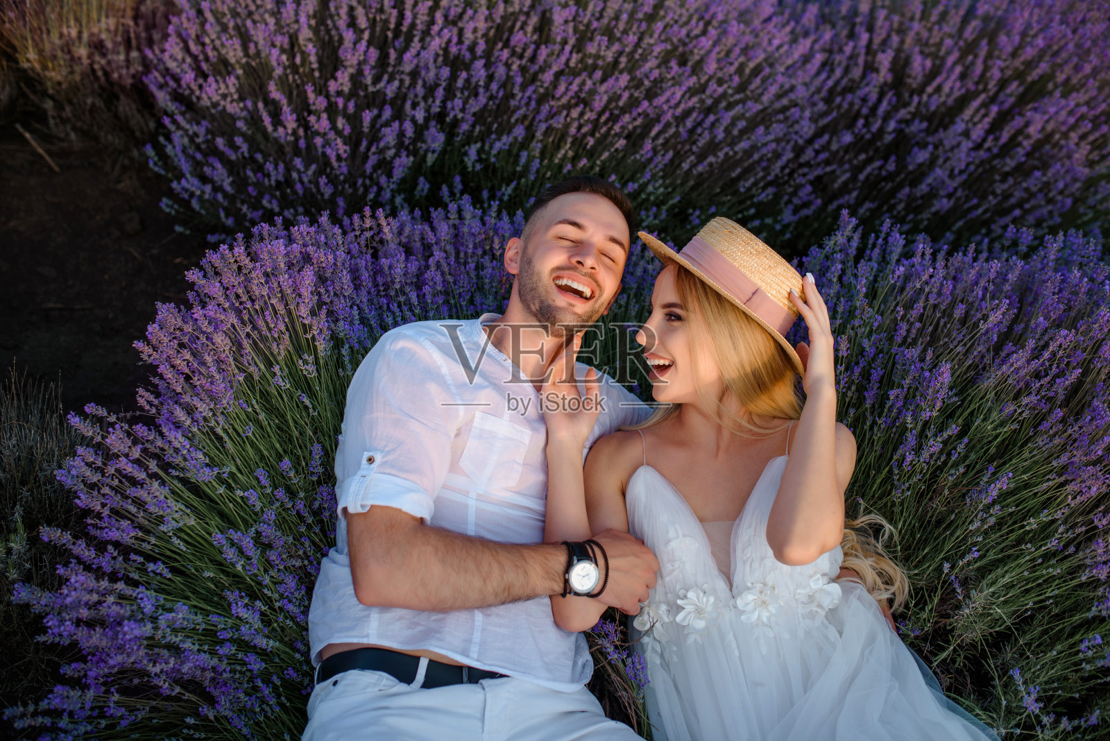 穿白色连衣裙和戴帽子的女人与穿白衬衫的男人走在薰衣草田里照片摄影图片
