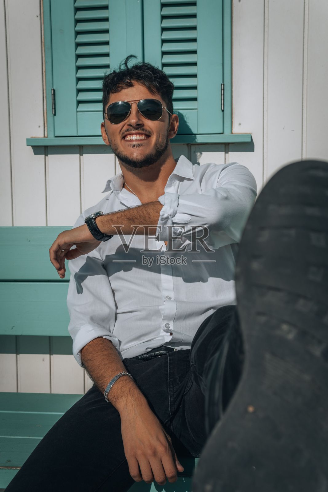 垂直拍摄的年轻性感迷人的男性在白衬衫和太阳镜摆姿势照片摄影图片