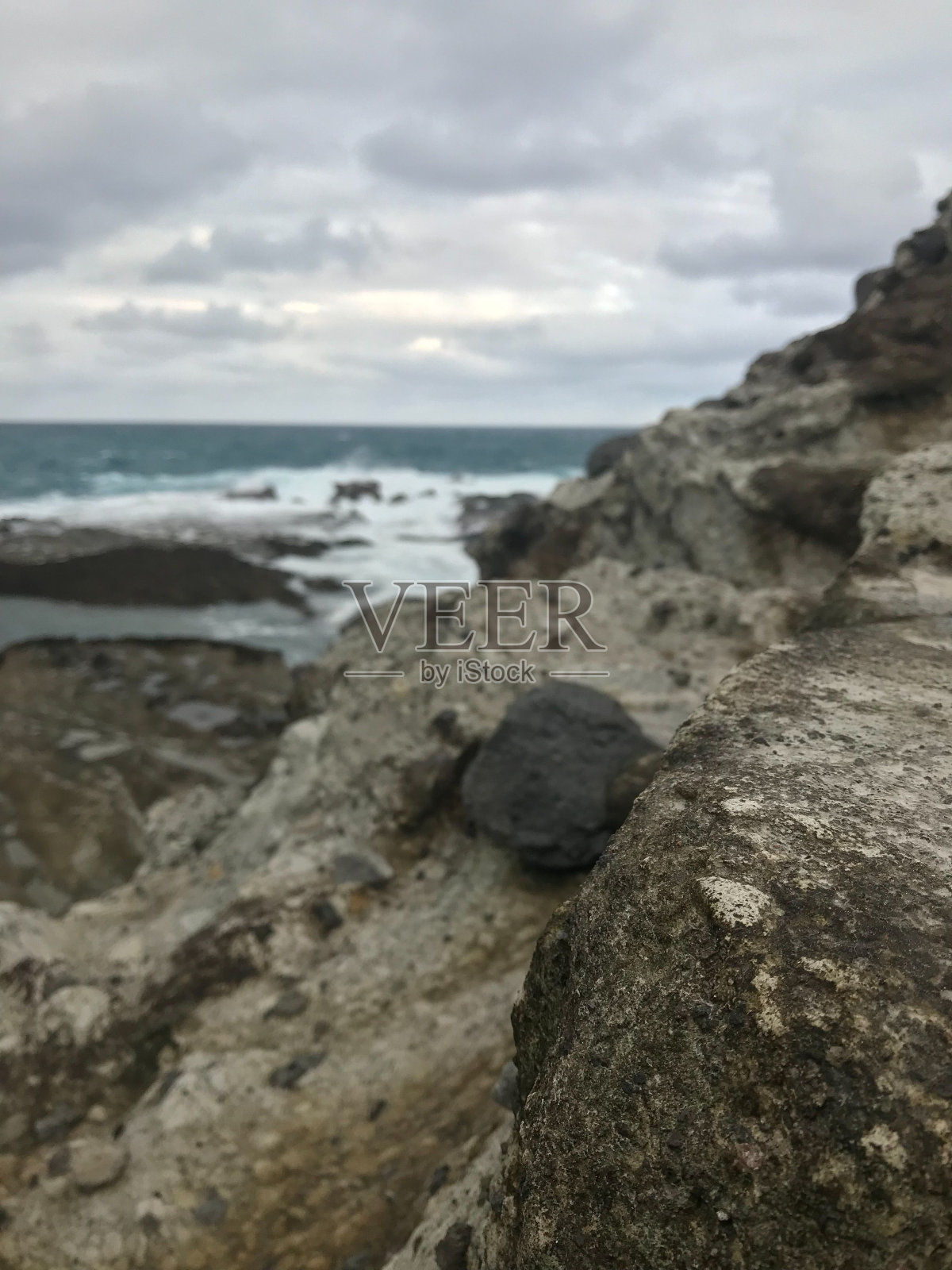 多云天空下岩石海岸和海景的垂直视图照片摄影图片