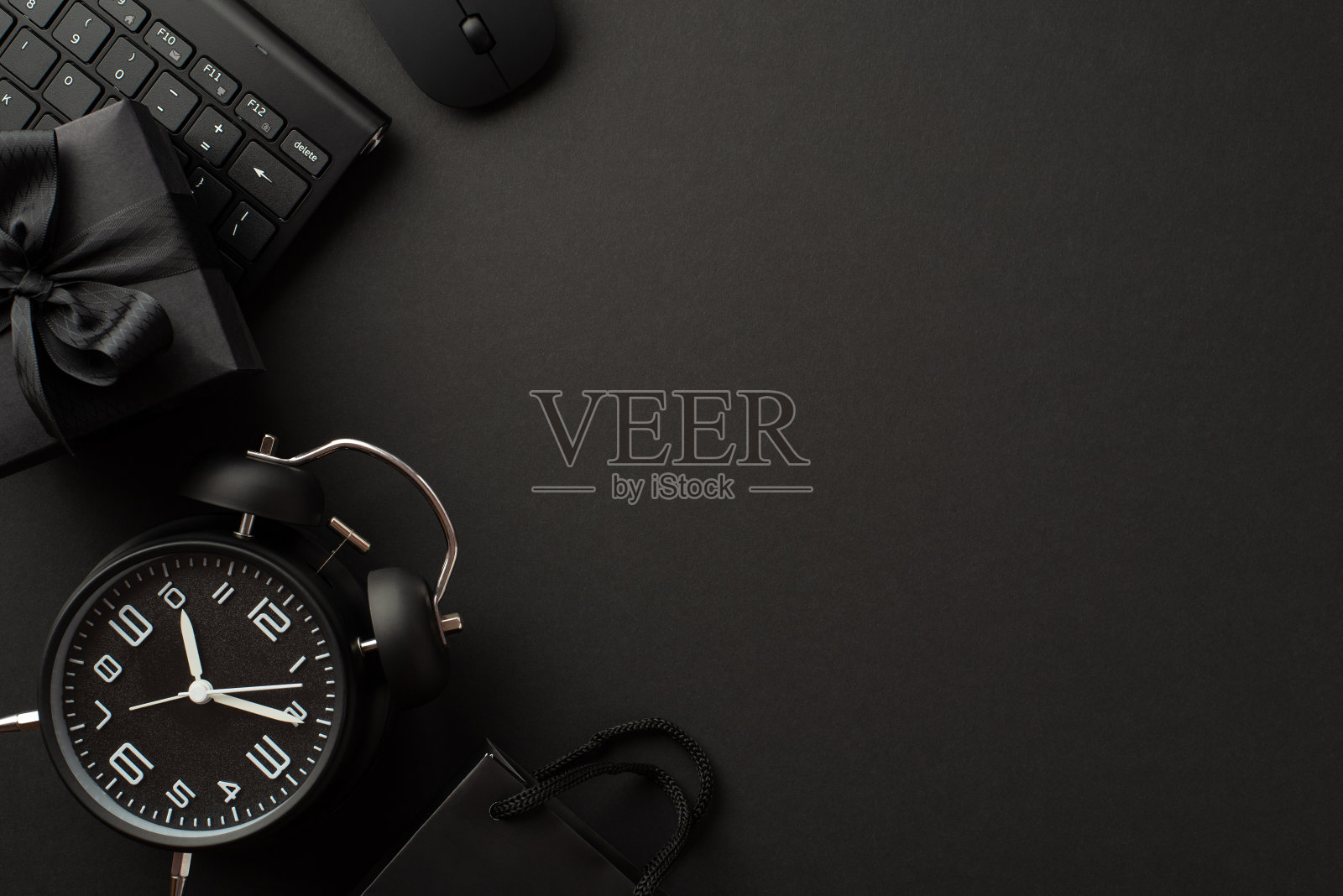 “黑色星期五”的概念。顶视图照片黑色闹钟礼盒丝带蝴蝶结纸袋电脑鼠标和键盘上孤立的黑色背景与copyspace照片摄影图片