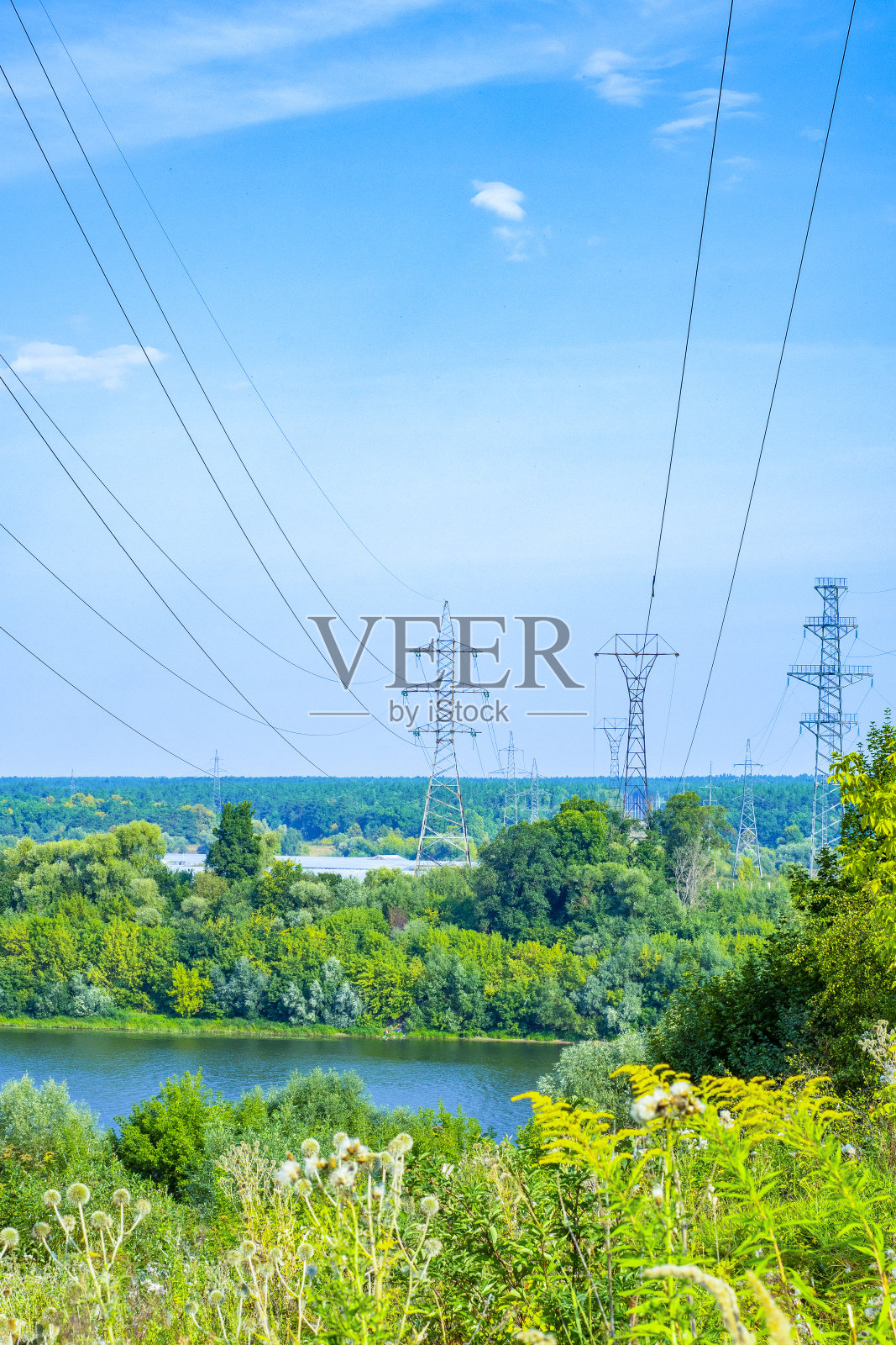 乡村电力传输线以树木和河流为背景。偏远地区三相输配电系统。演讲的背景或书的封面照片摄影图片