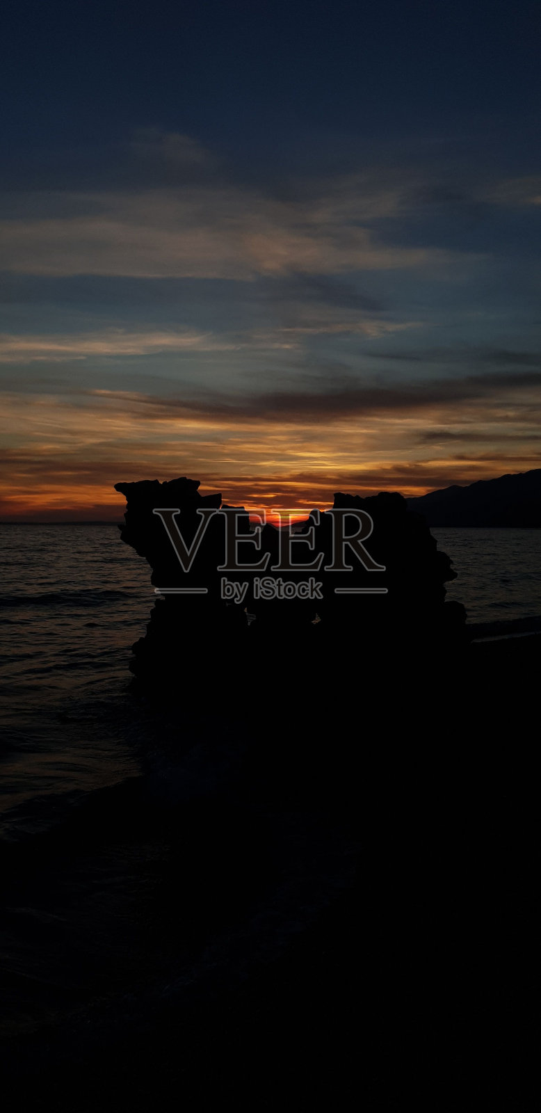 日落时海洋背景下的岩层剪影照片摄影图片