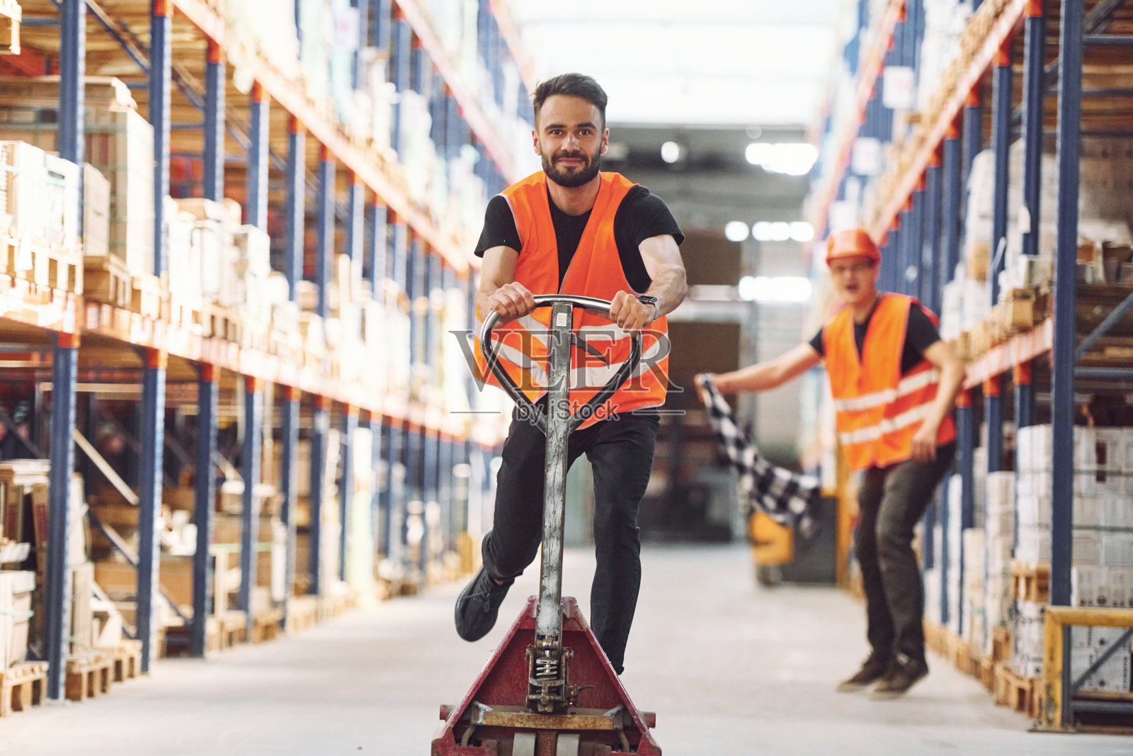 男人骑着电车站台。的乐趣。仓库里有两个仓库工人照片摄影图片