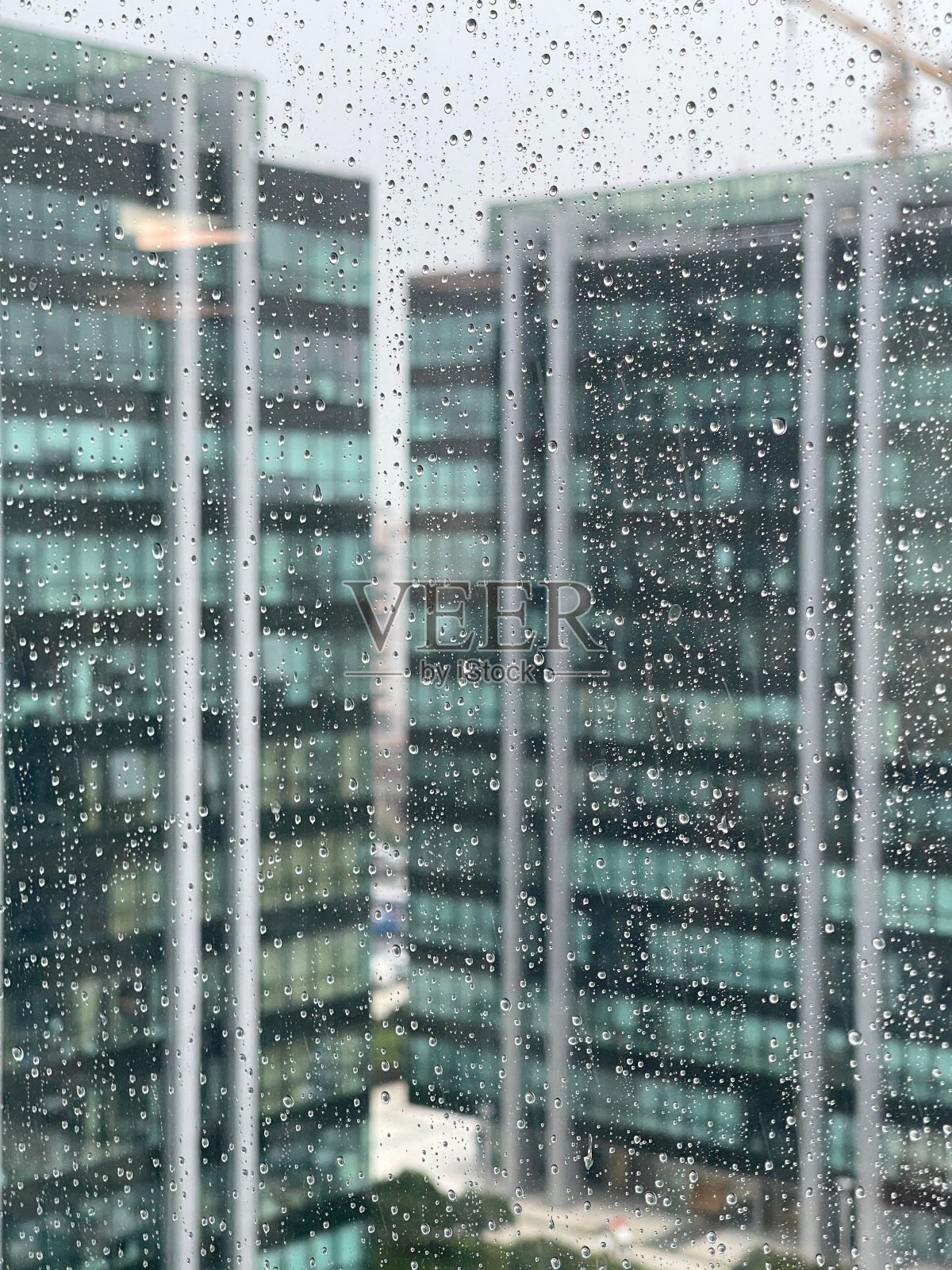 雨点落在窗户上,背景是摩天大楼。照片摄影图片