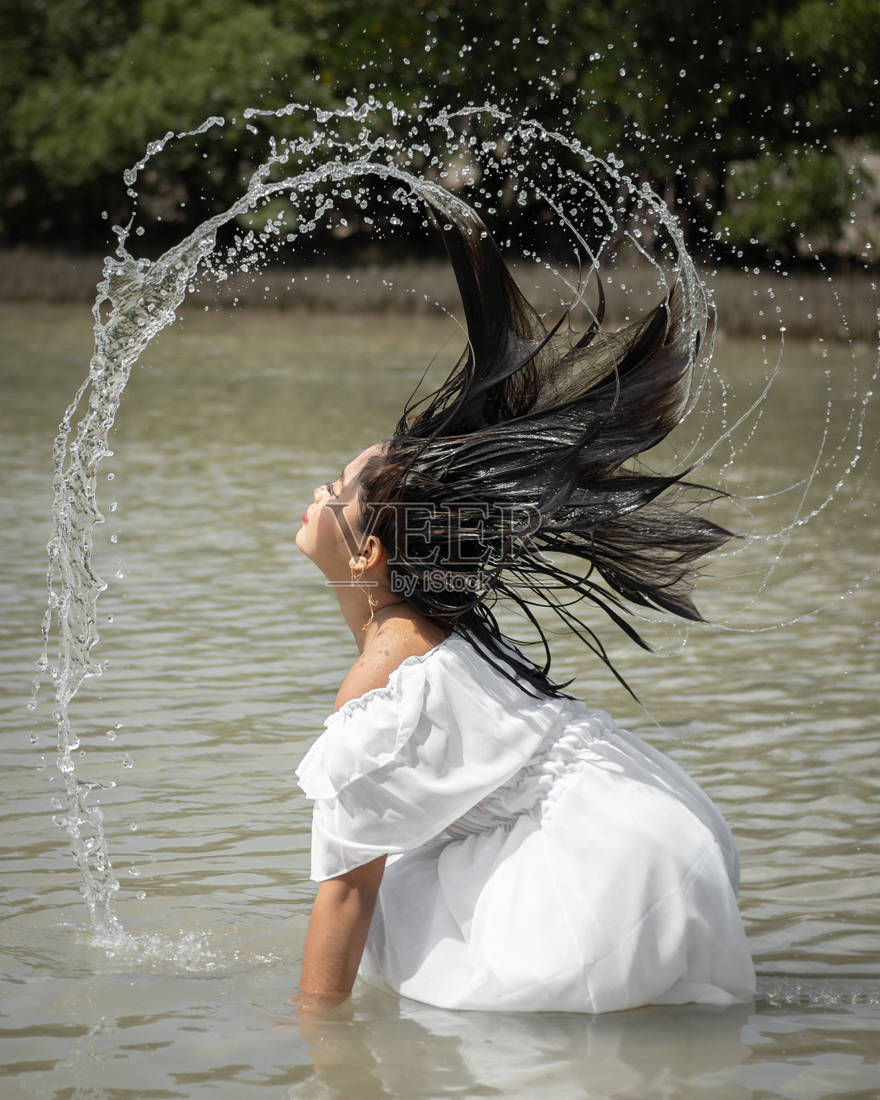 东南亚湿女孩在白色的裙子赤脚站在海洋做水喷雾照片摄影图片