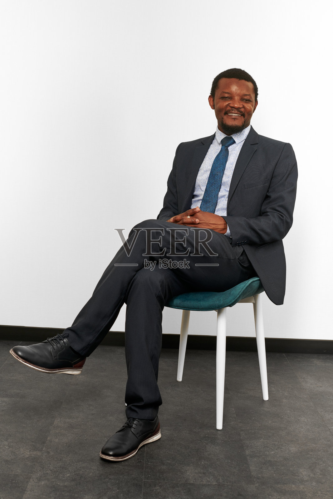 微笑的非裔美国黑人西装坐在椅子上交叉手指照片摄影图片