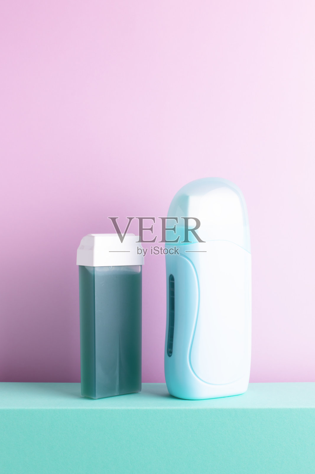 绿薄荷便携式脱毛蜡加热器和脱毛绿色蜡滚筒站在装饰的讲台上。照片摄影图片