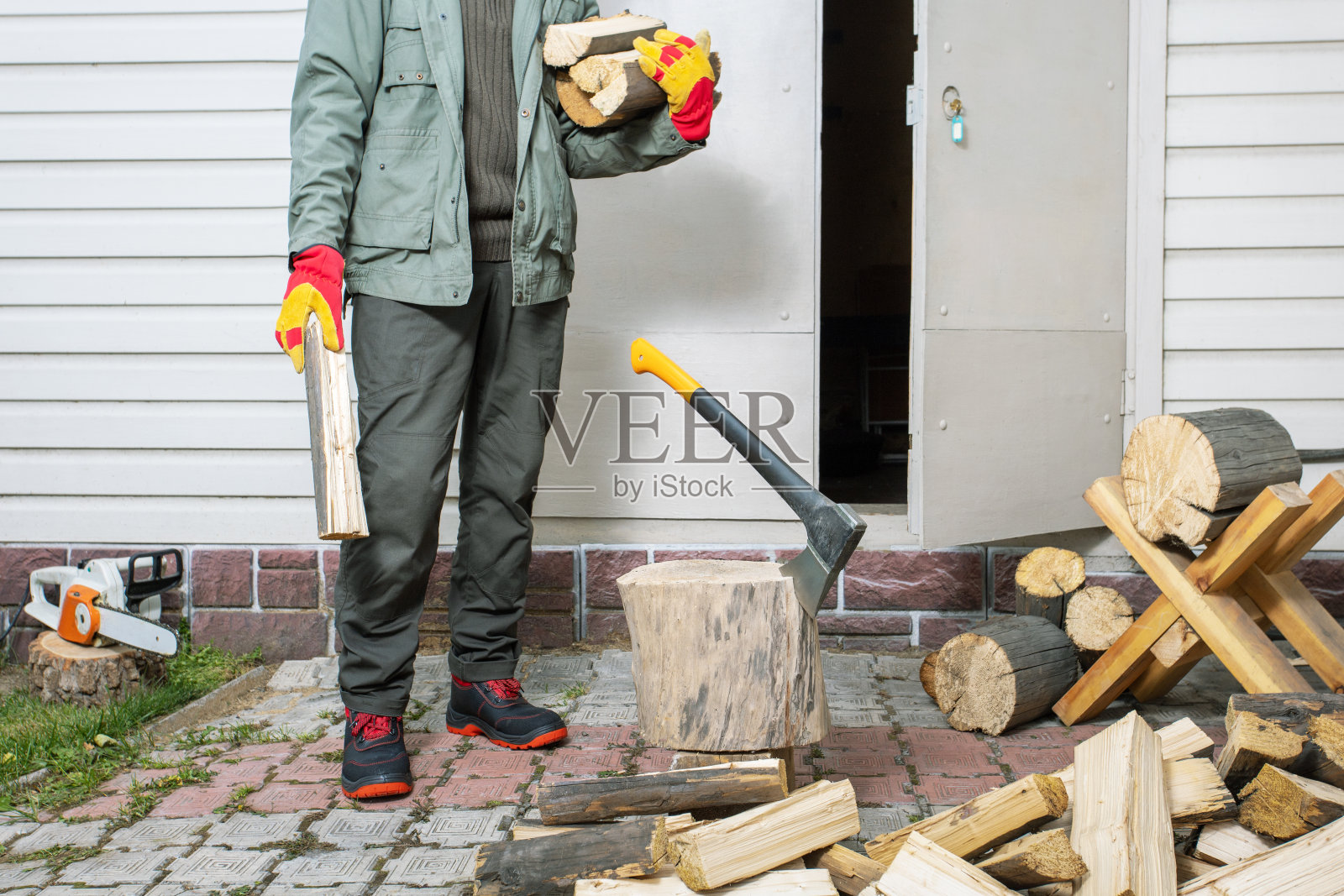 拿着一堆劈柴的人。为房子供暖准备木柴的概念。照片摄影图片