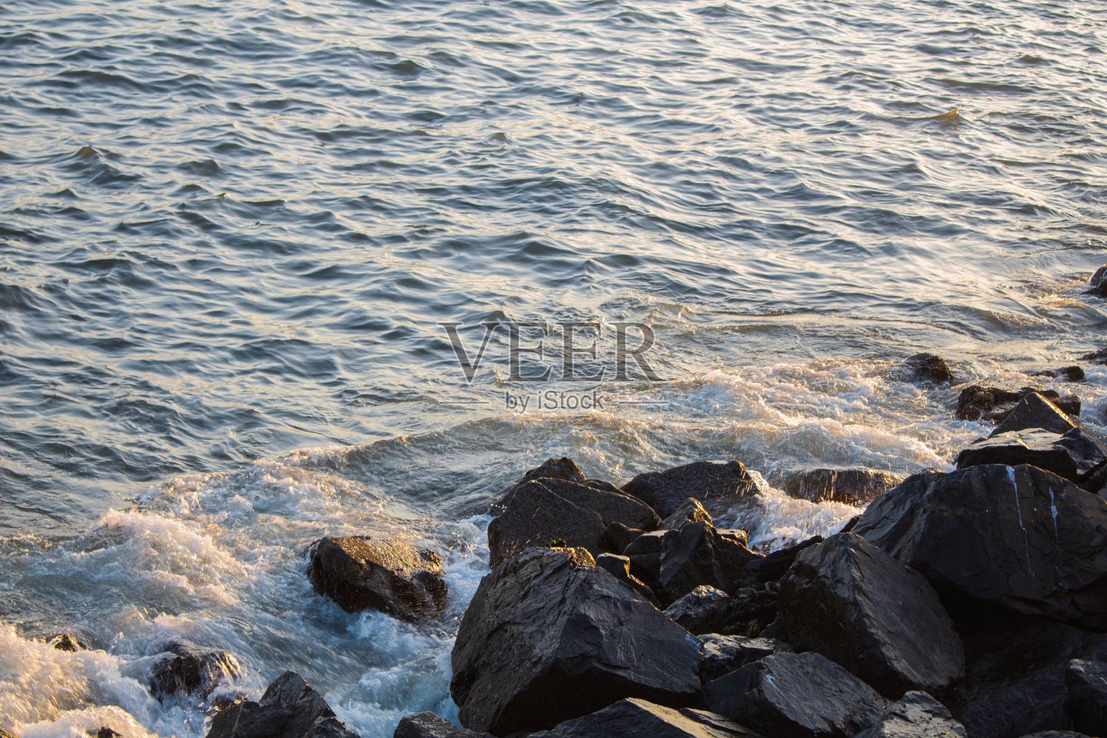 秘鲁钦博特海滩上的一堆岩石,日落时分,潮水冲刷着它们照片摄影图片