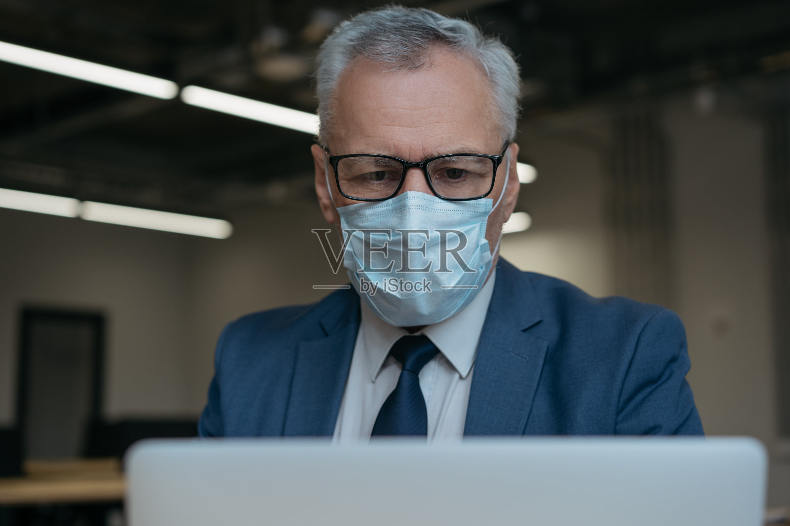 戴着医用口罩的男子使用笔记本电脑,交流,上网,在家工作照片摄影图片