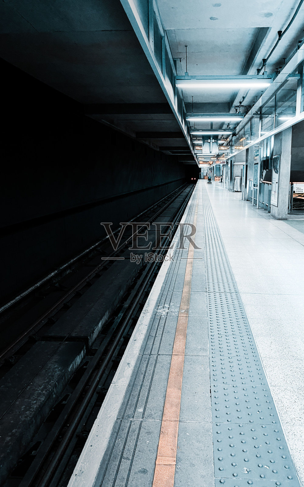 垂直拍摄的一个空的现代地铁站站台在晚上的方向标志照片摄影图片