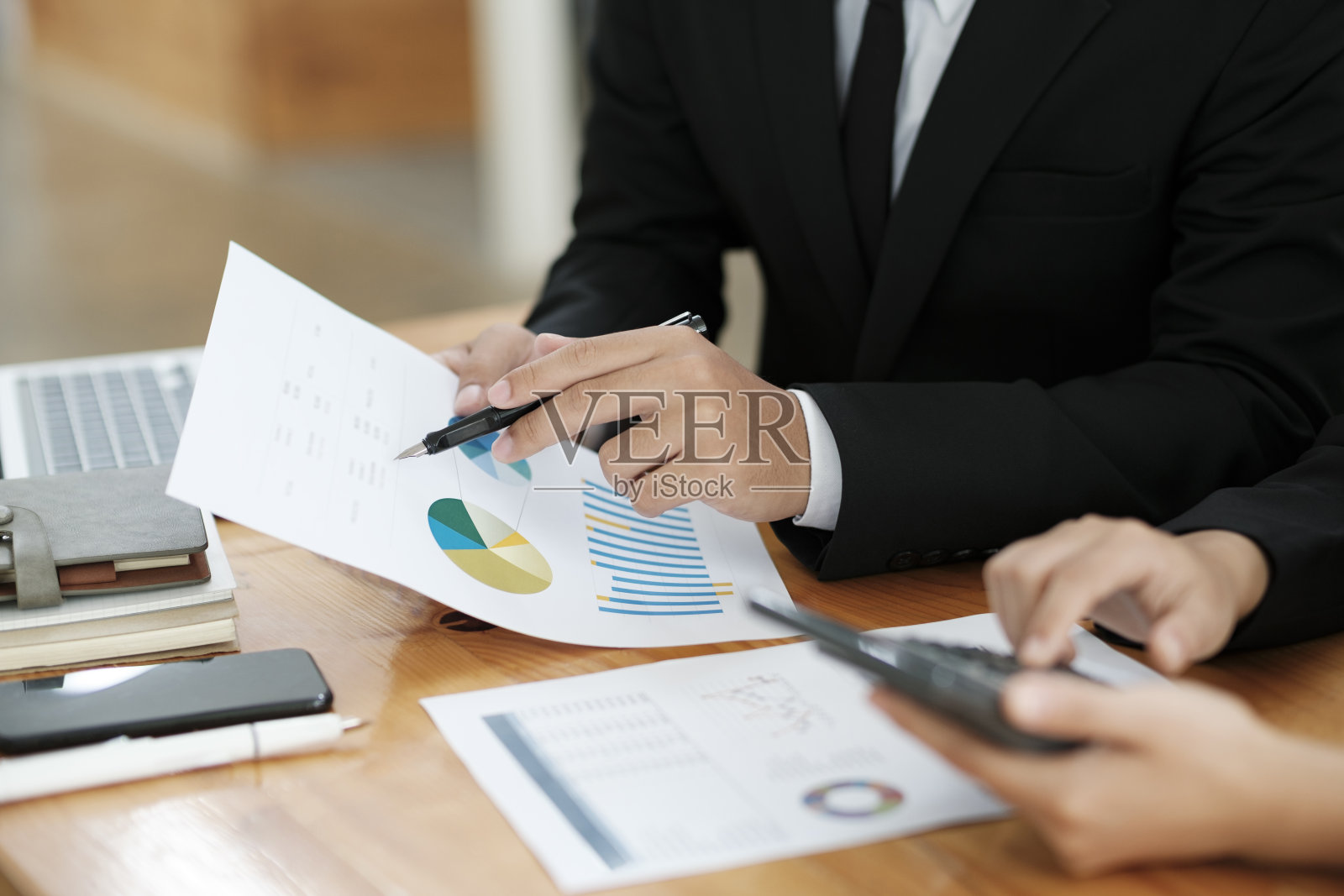 商人们用笔记本电脑和图表工作、讨论、分析。照片摄影图片