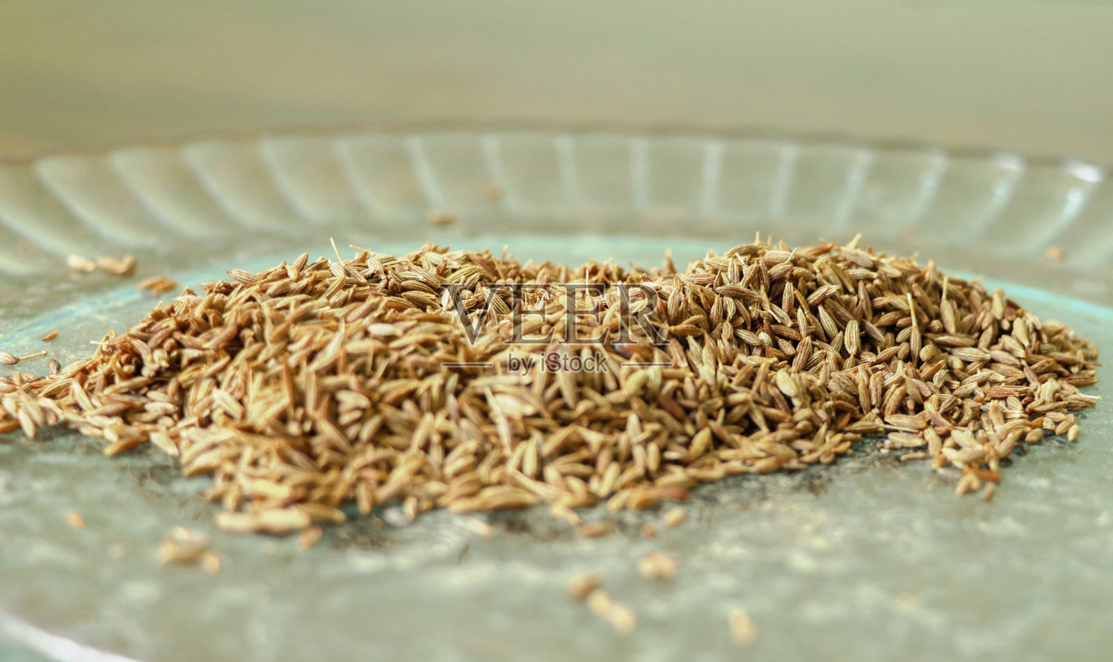 孜然种子(Jeera)在一个盘子在木制背景。照片摄影图片