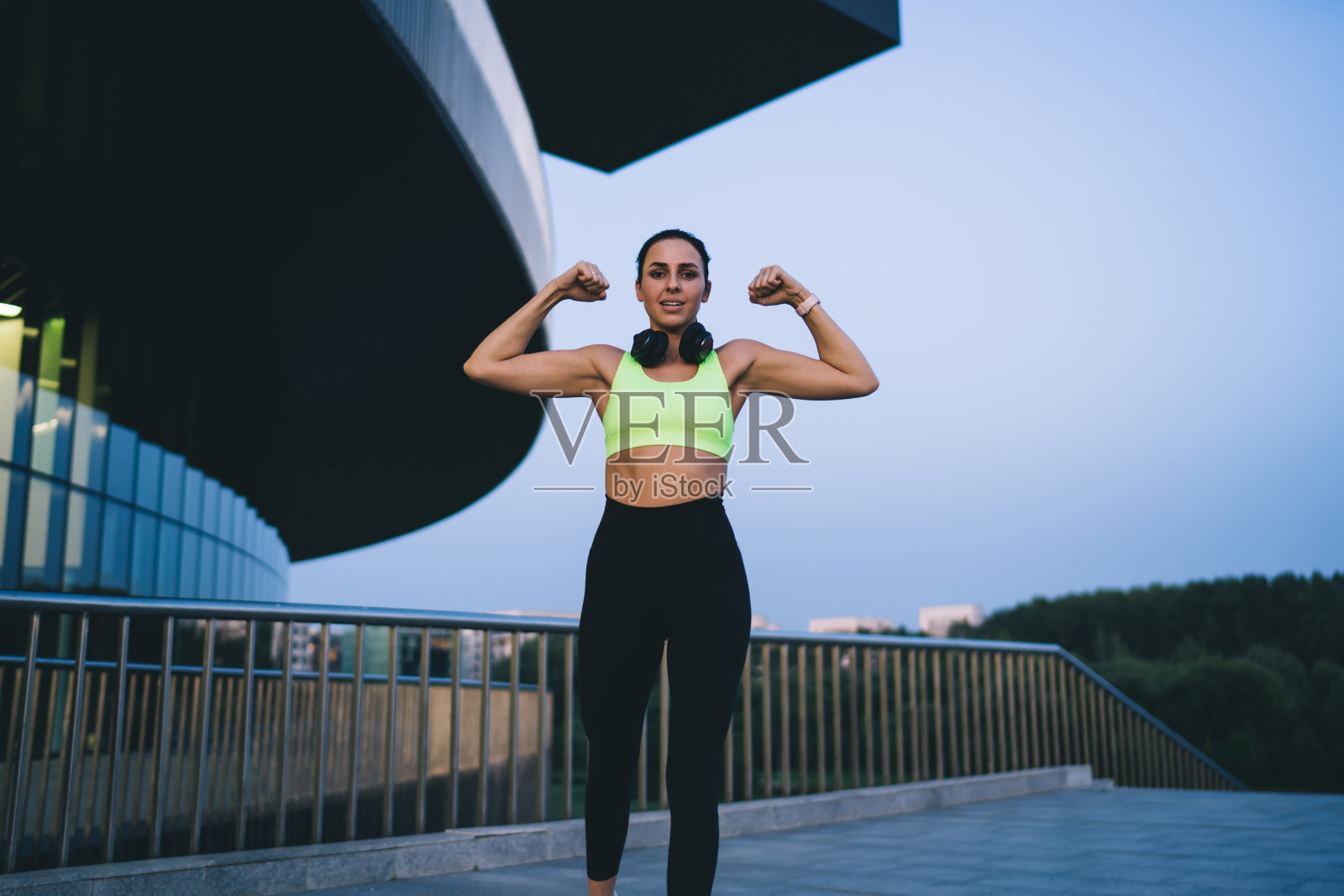 健身女子在桥上锻炼时弯曲肱二头肌照片摄影图片