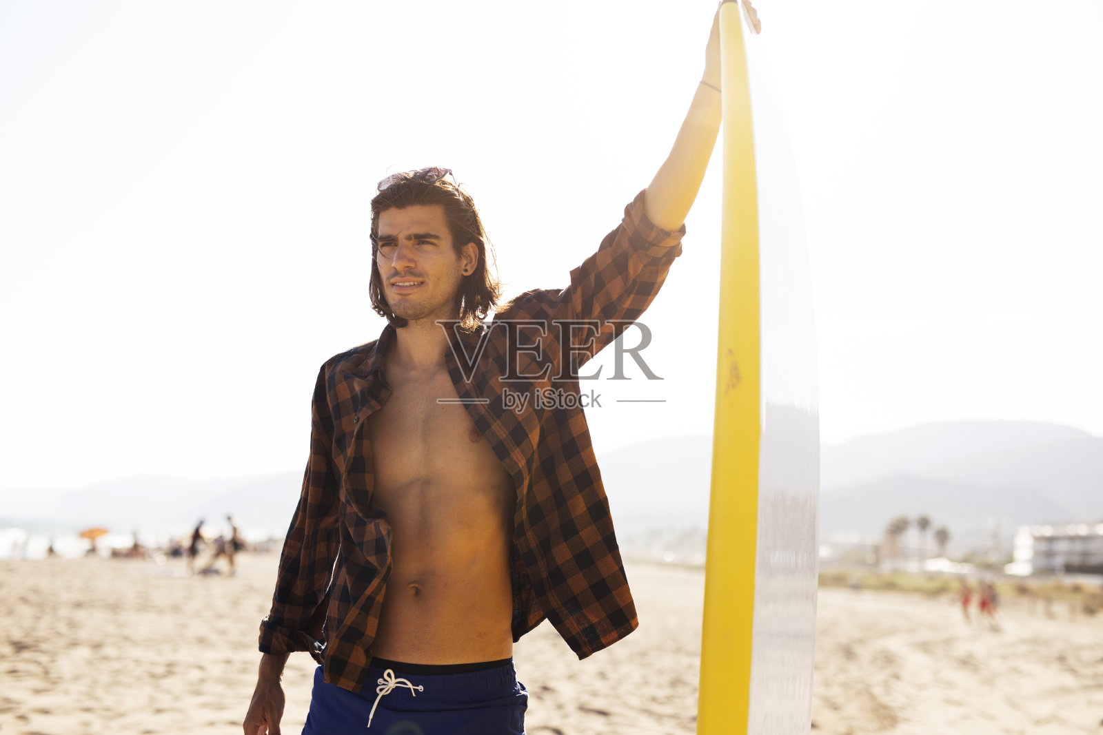 海滩上一个拿着冲浪板的年轻人。照片摄影图片