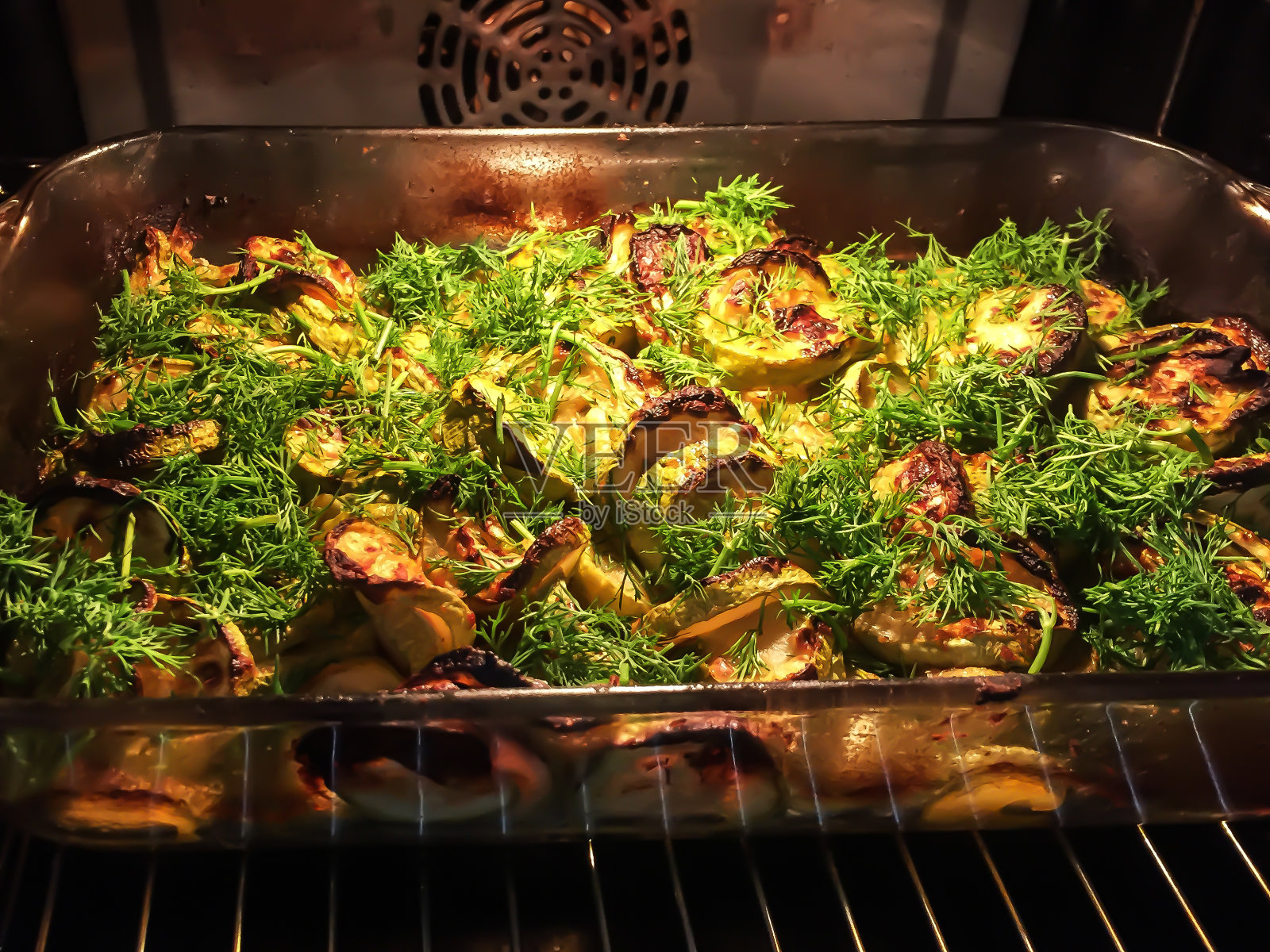 烤箱里烤西葫芦配绿色蔬菜。照片摄影图片