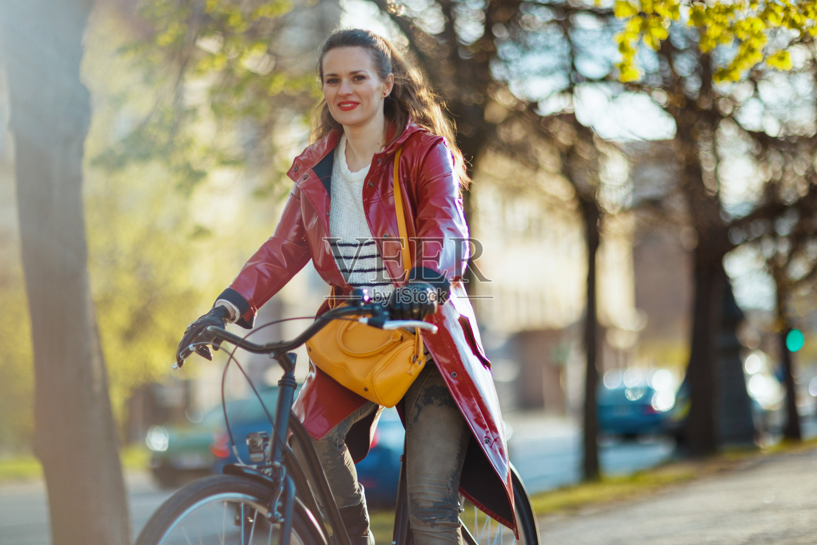 现代女性穿着红色雨衣在城市户外骑自行车照片摄影图片