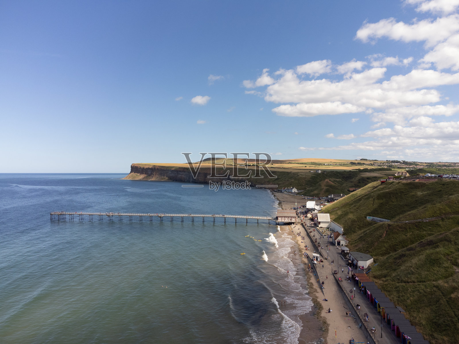 英国北约克郡萨尔特本的空中海岸线场景,冲浪者在平静的北海上。用0级无人机拍摄的照片摄影图片