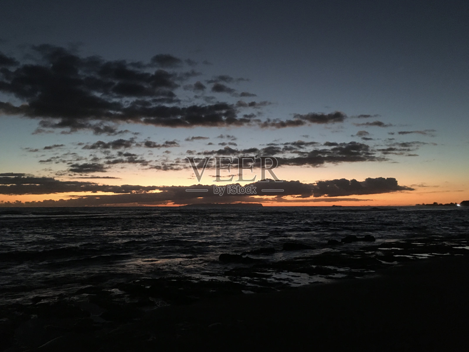 十月日落在夏威夷考艾岛上的凯卡哈——地平线上的纽豪岛。照片摄影图片