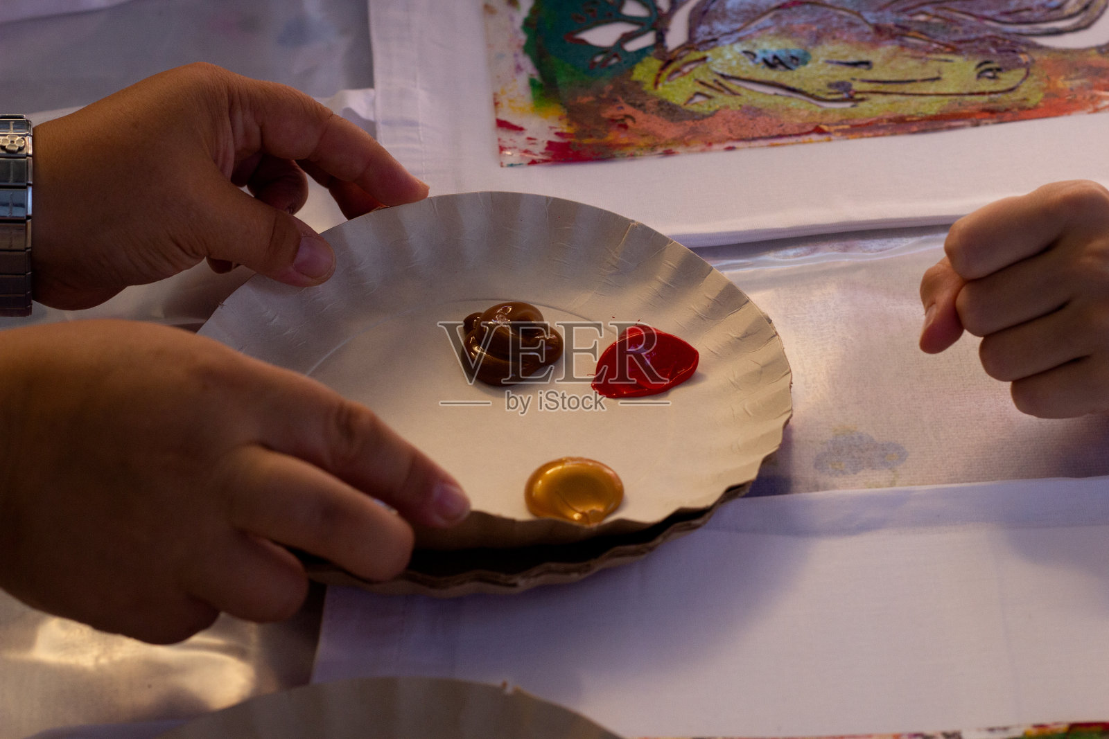 手端着涂有丙烯酸颜料的调色板。照片摄影图片