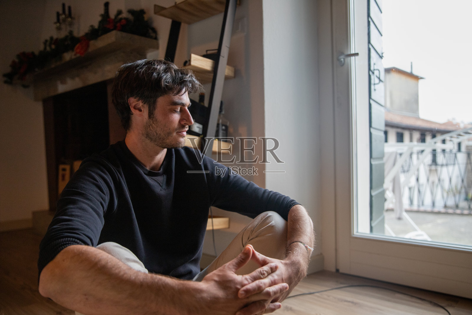 坐在地板上交叉双臂的年轻男子,心理健康概念照片摄影图片