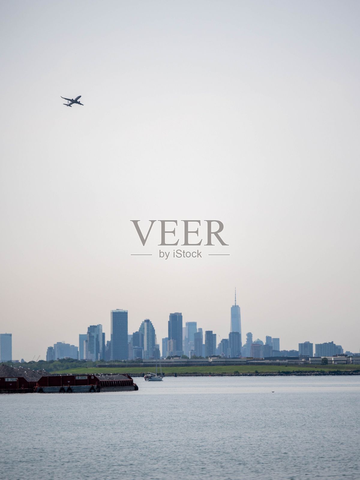 垂直拍摄的飞机飞过美丽的大海,背景是城市景观照片摄影图片