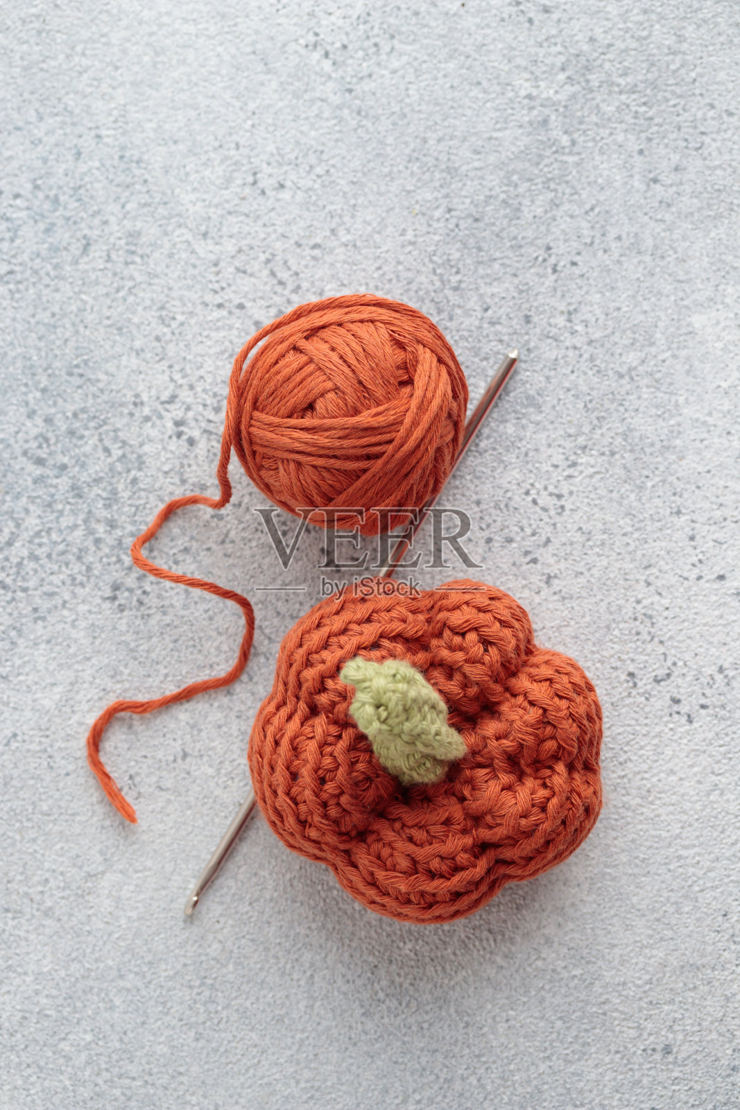 可爱的钩针针织橙色南瓜在灰色背景照片摄影图片